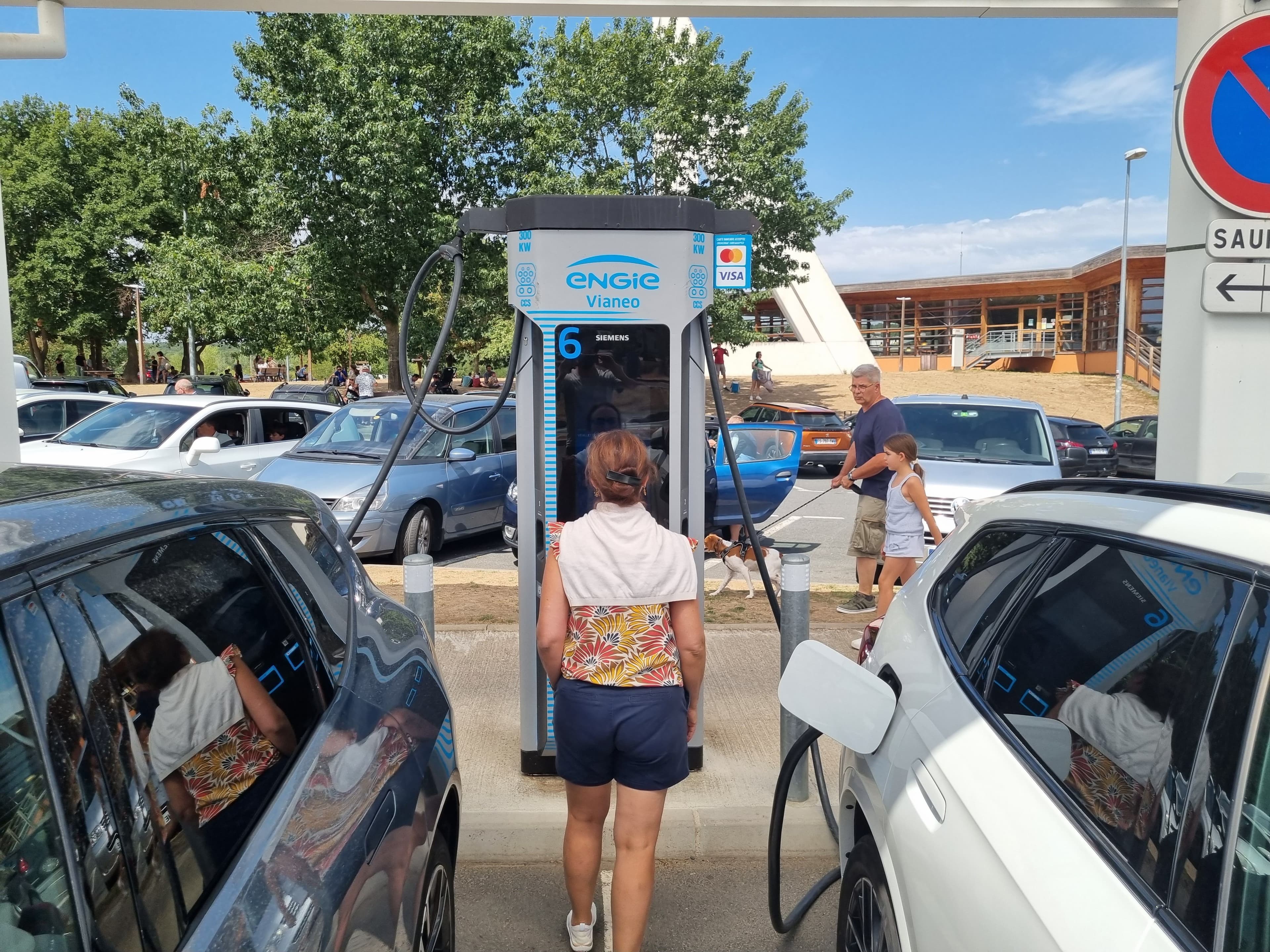Une automobiliste recharge sa voiture électrique sur une aire d'autoroute.