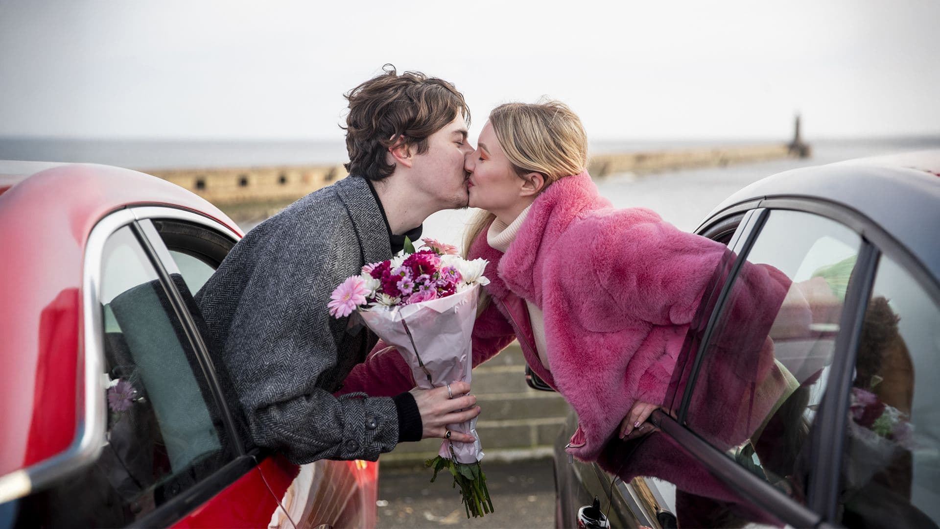 Deux amoureux s'embrassant à l'extérieur de leur voiture.