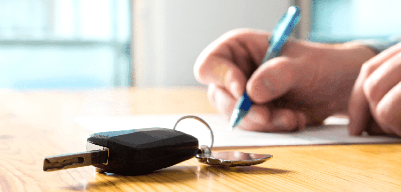 Un automobiliste qui signe un papier au sujet de sa voiture