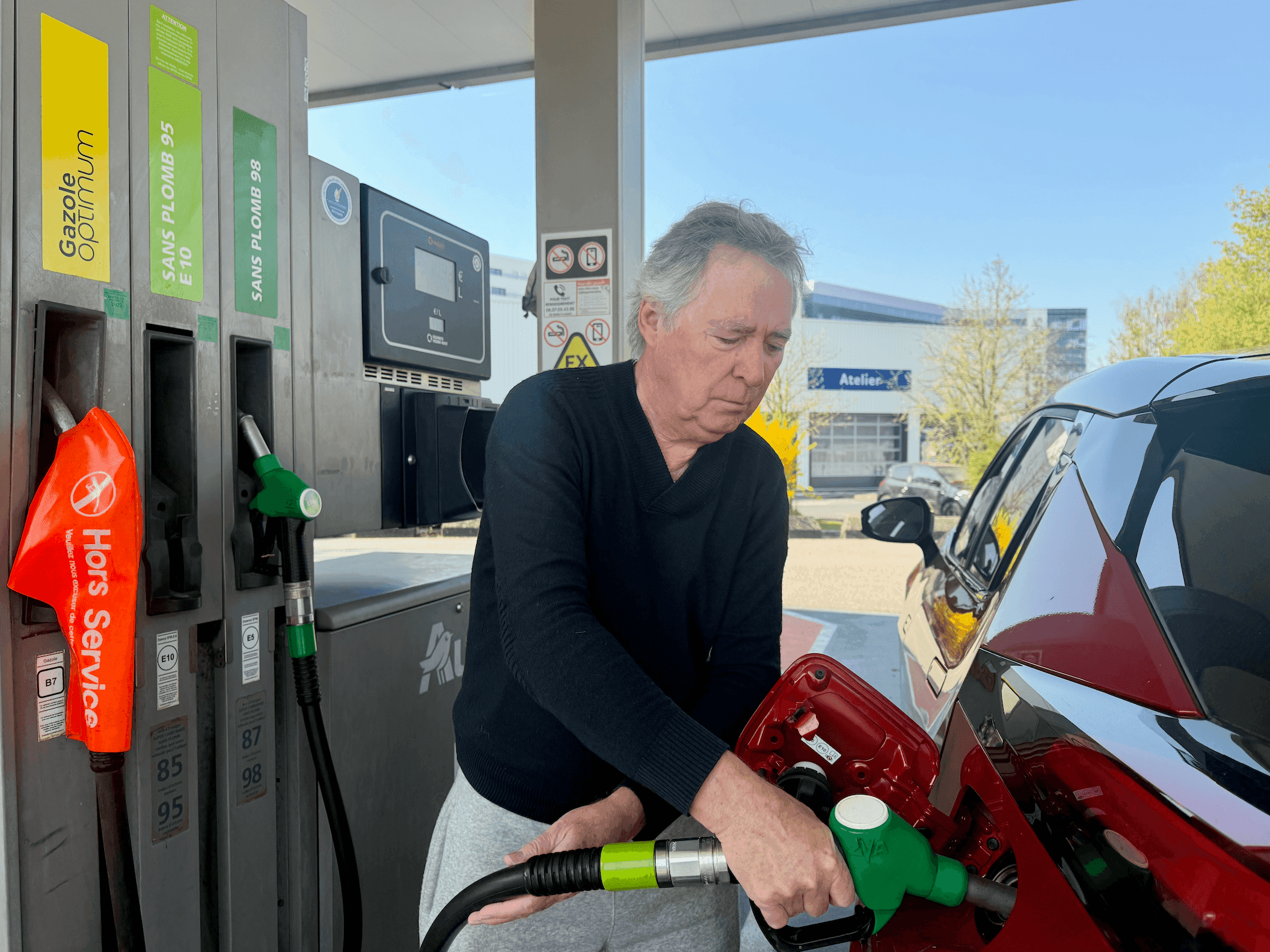 Un homme faisant son plein à la station-service.