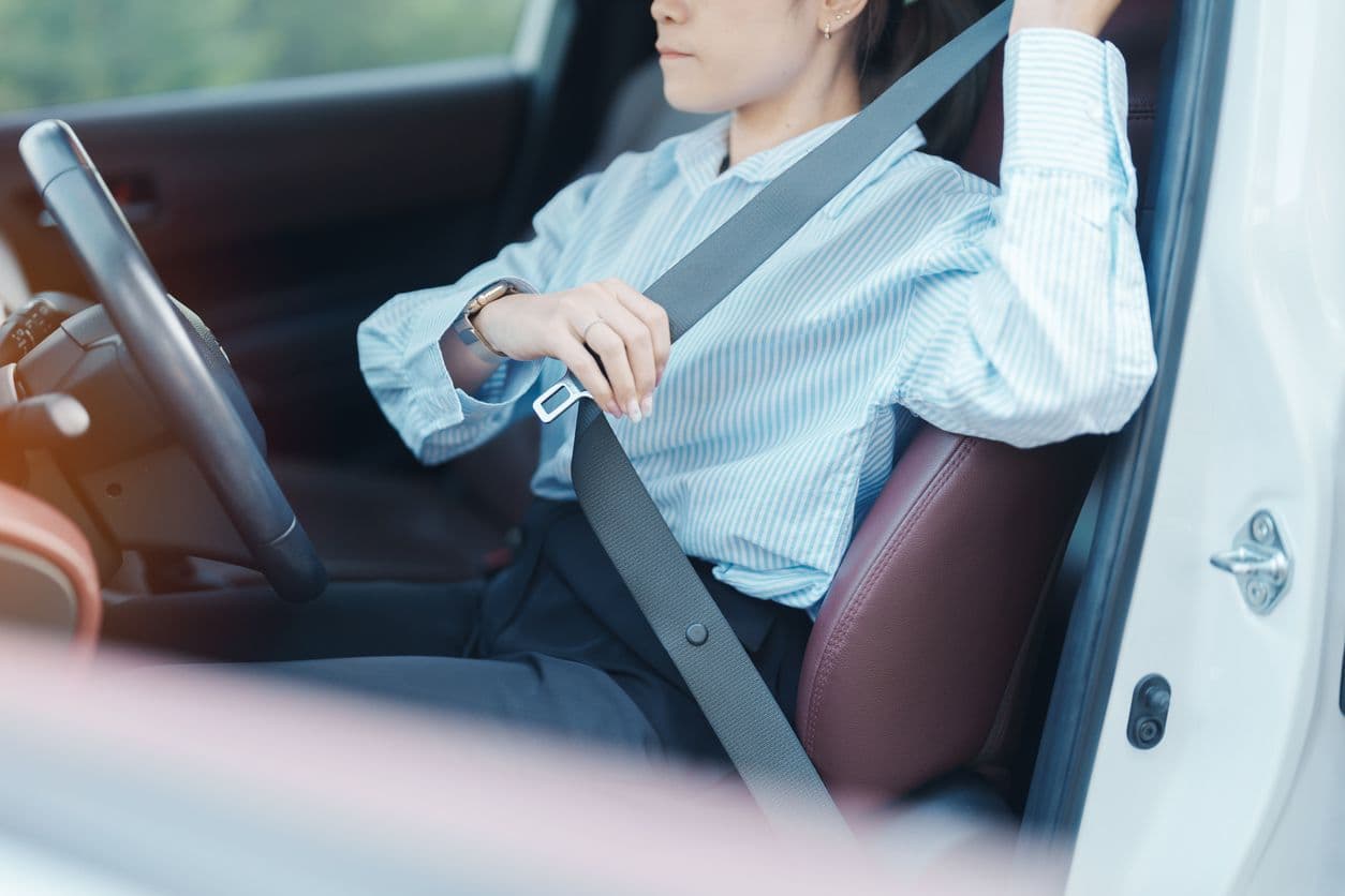Une femme en train de mettre sa ceinture de sécurité. 