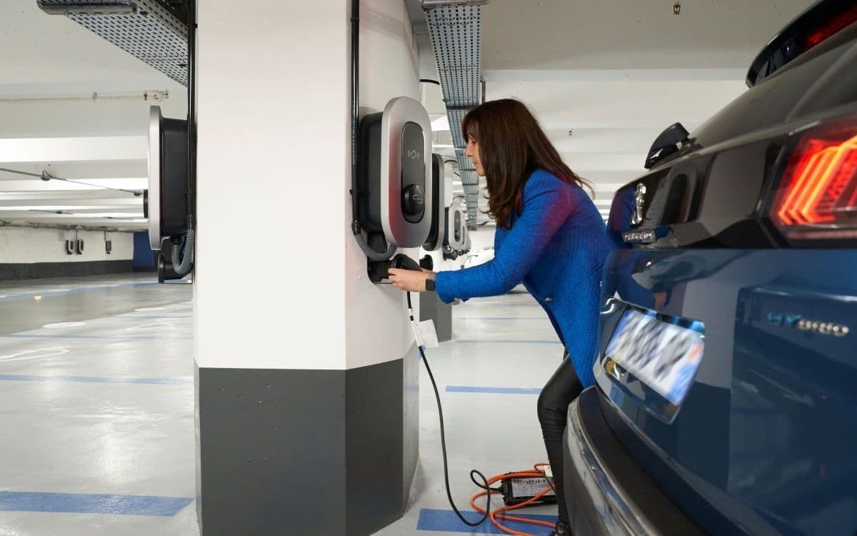 Un conducteur de voiture électrique recharge sa voiture dans un parking