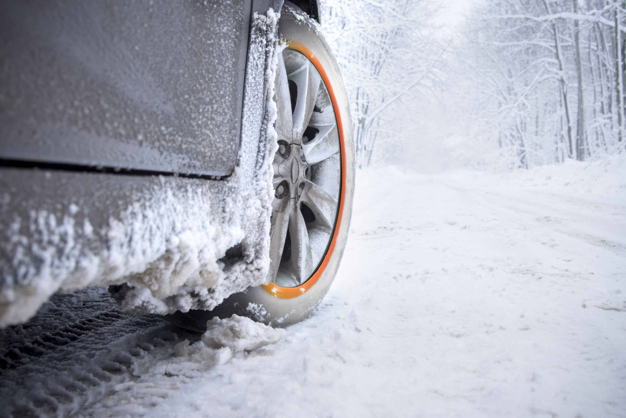 Une chaussette Musher sur la roue avant d'une voiture sur route enneigée