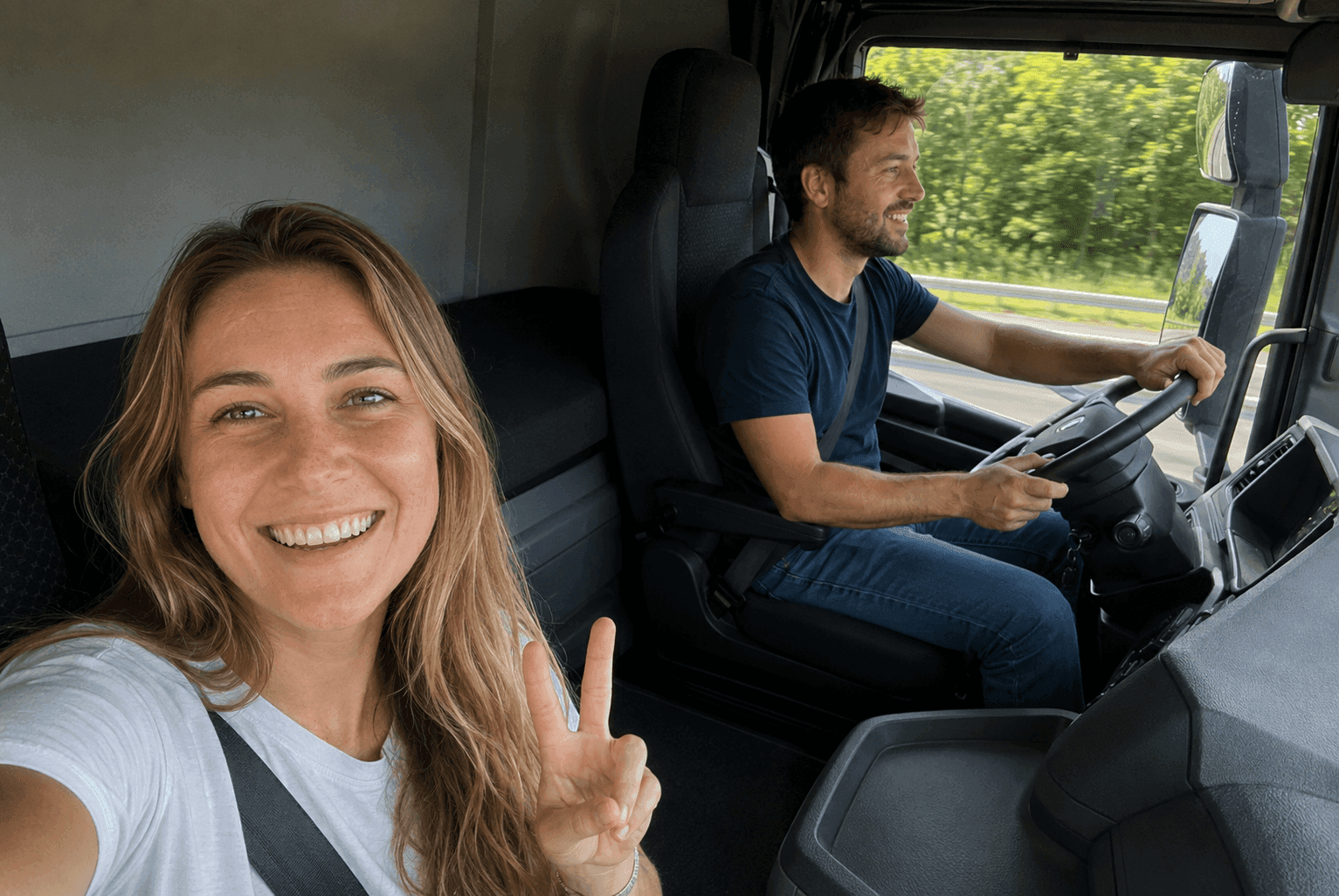 Deux personnes souriantes dans la cabine d’un camion en mouvement