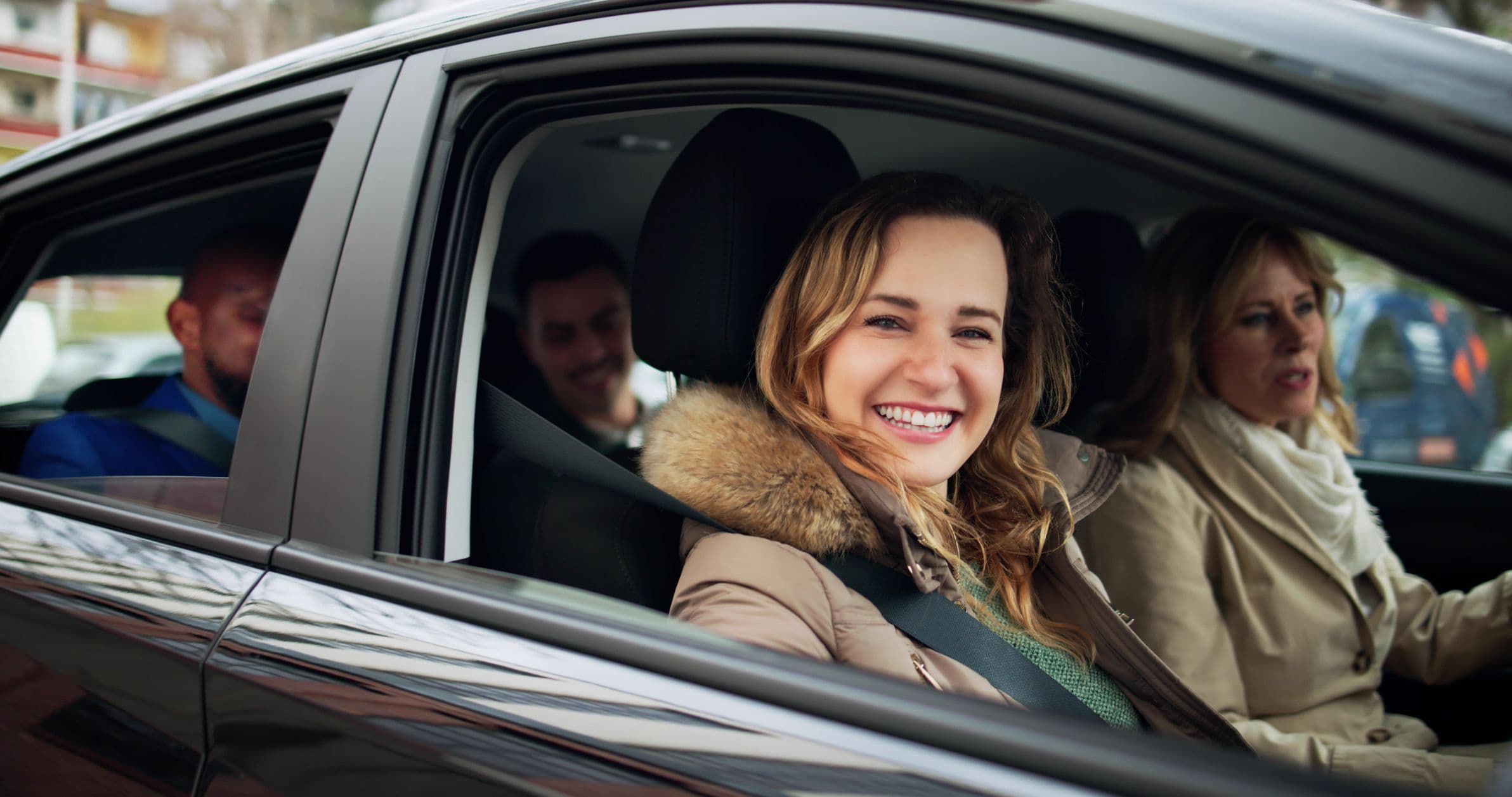 Des passagers souriants dans une voiture.