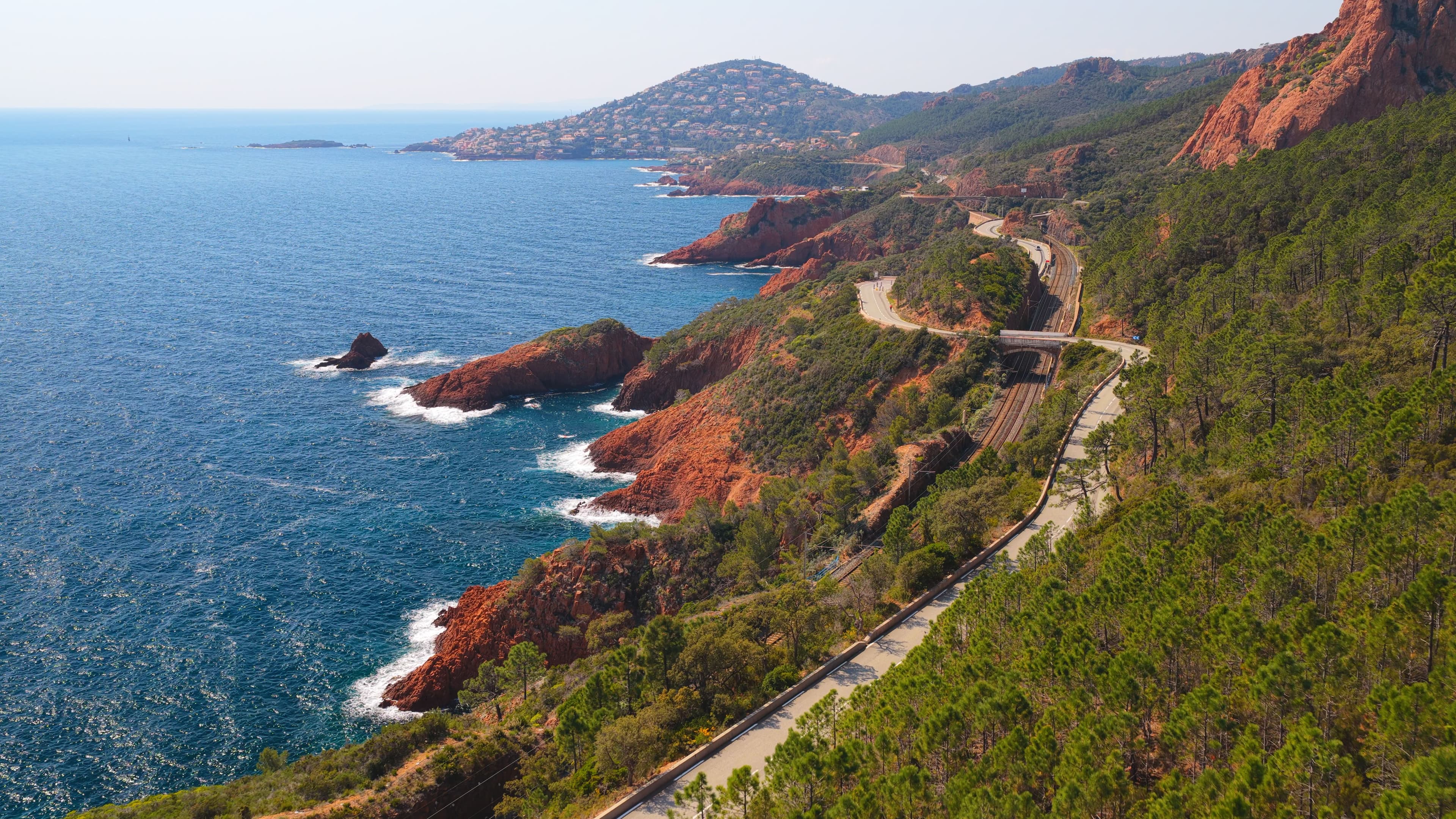 La route de la corniche de l'Estérel vue du ciel, avec les roches rouges du massif et de l'estérel et la mer méditerrannée