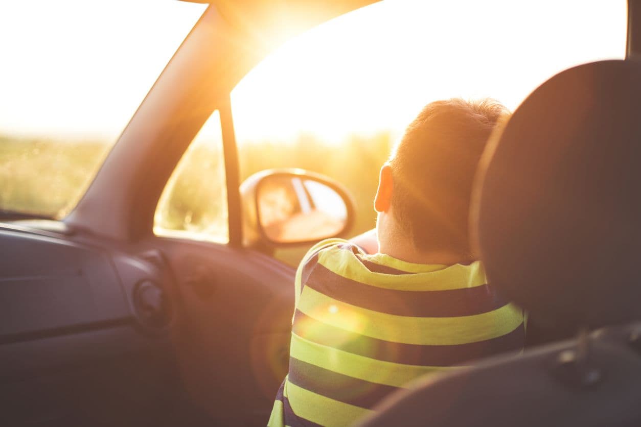 Un enfant assis côté passager qui regarde par la fenêtre.