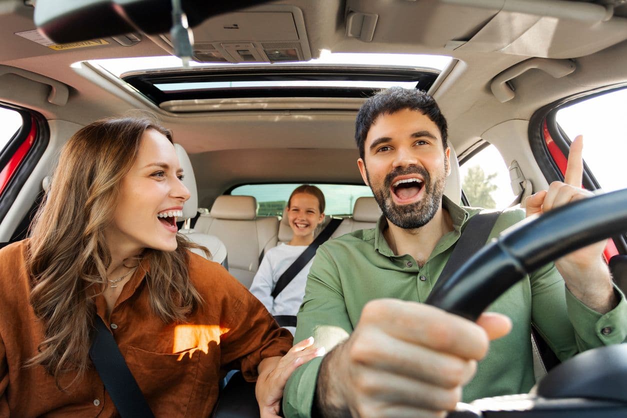 Un couple avec une enfant dans une voiture.