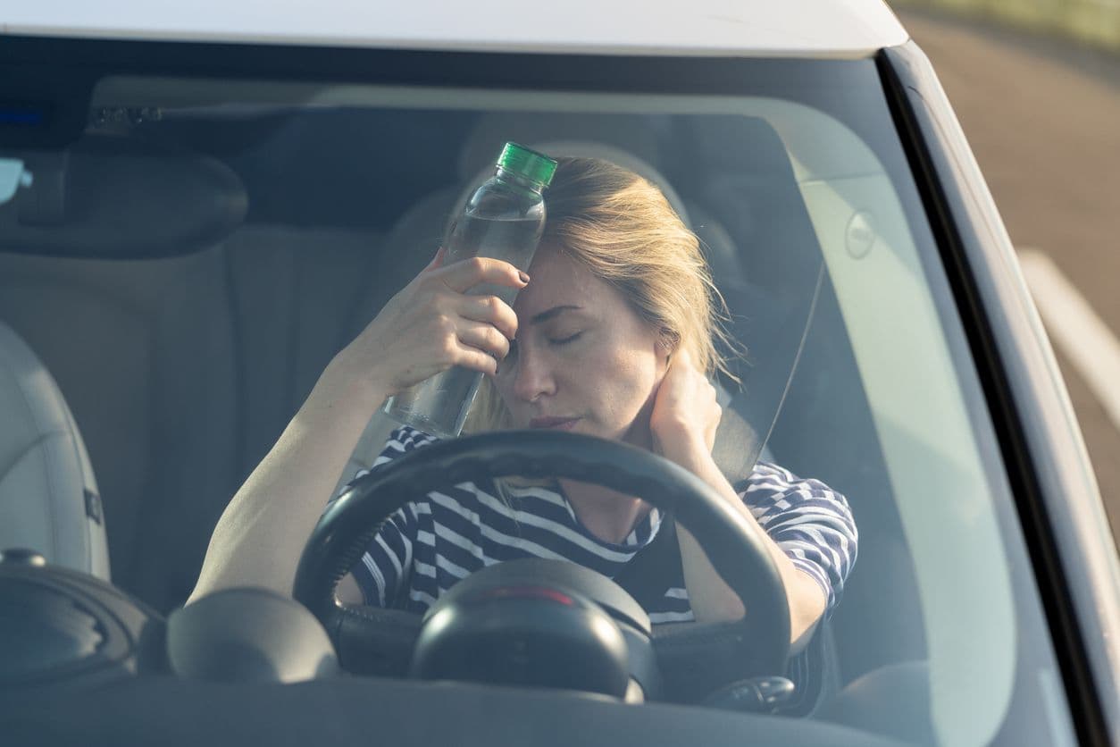 Femme qui tient une bouteille d'eau au volant de sa voiture.