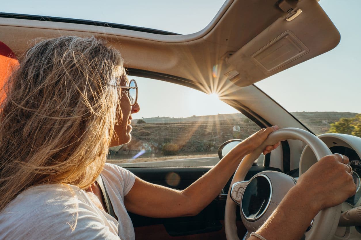 Une femme qui conduit en plein soleil.