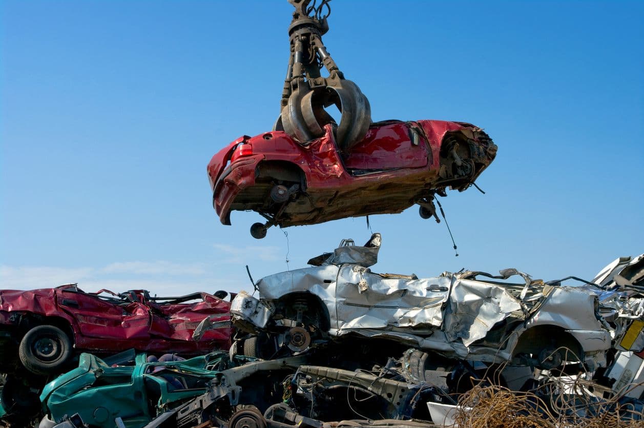 Photo d'une voiture à la casse soulevée par une grue.