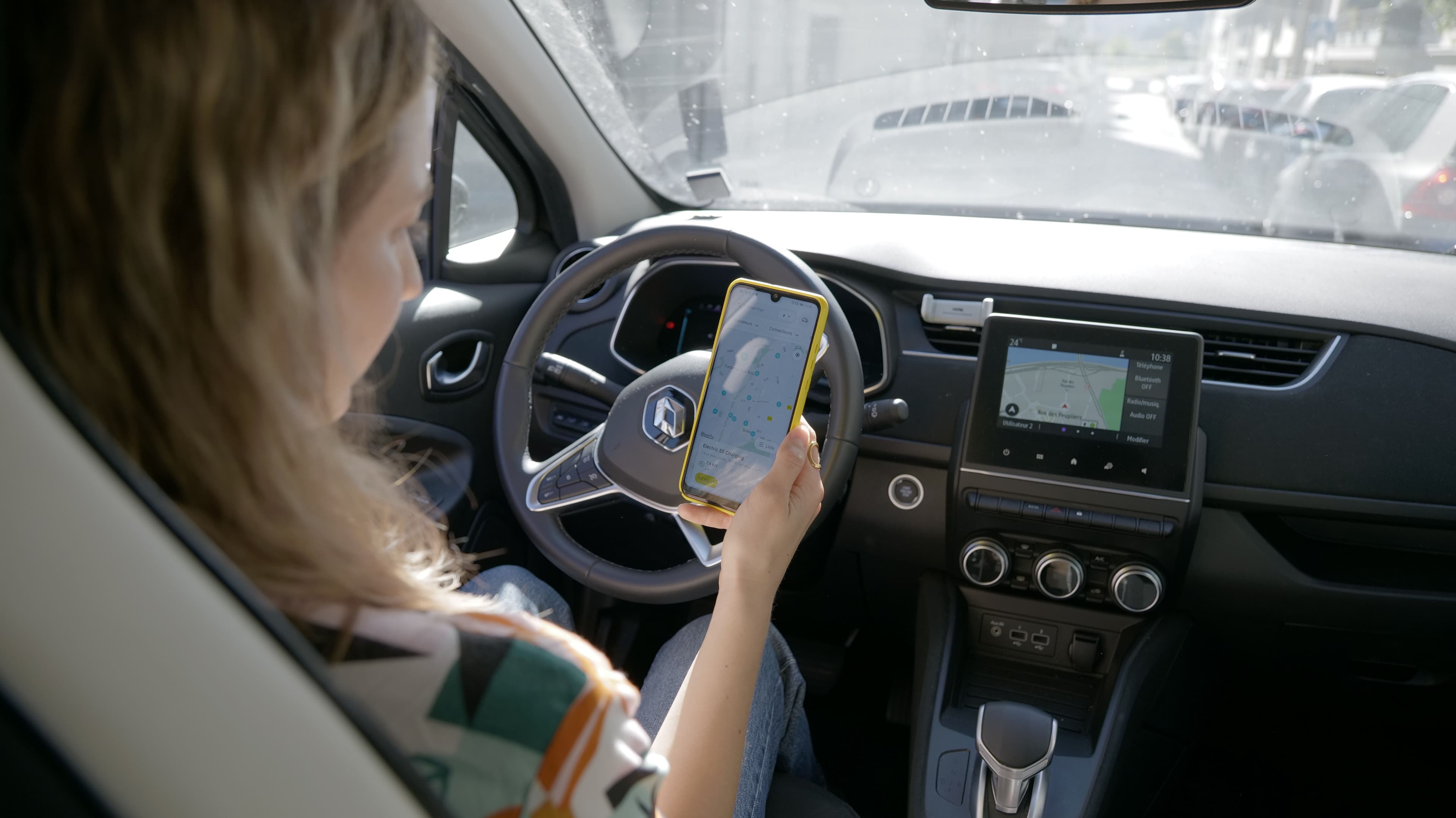 Une jeune femme en voiture utilise un GPS en mode Carplay et sur son téléphone.