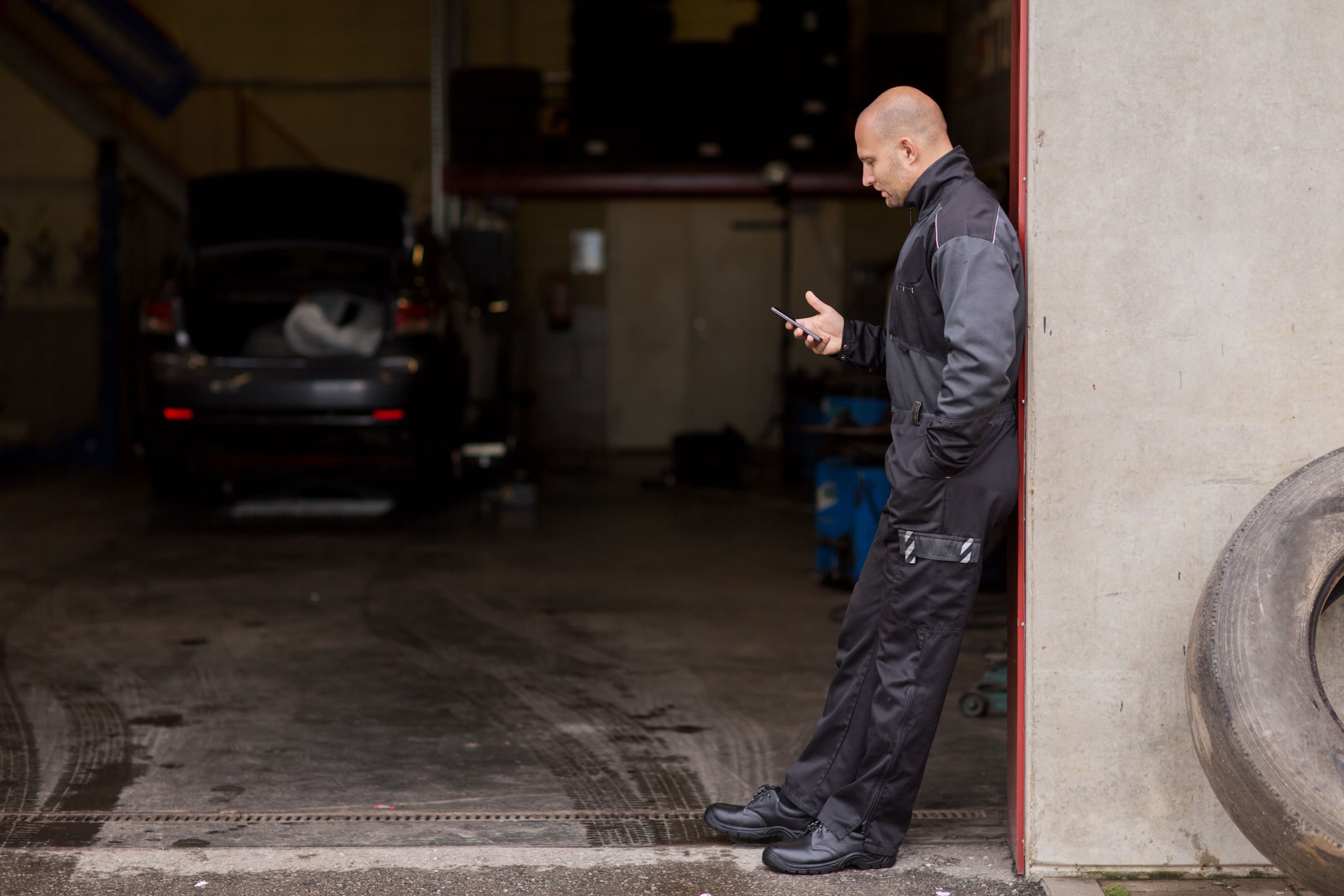Un mécanicien sur son téléphone dans un garage vide.