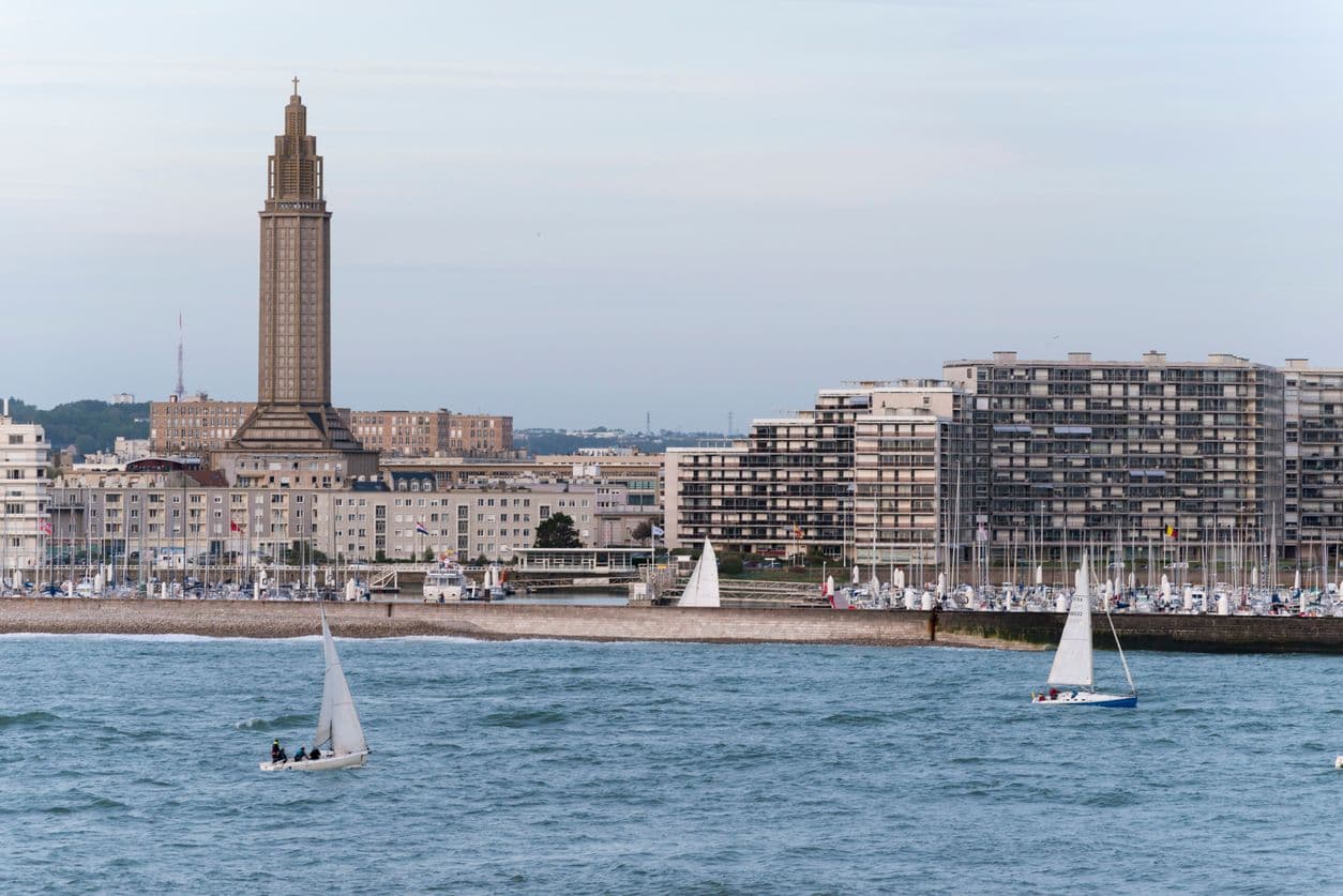 Vue sur la ville du Havre depuis la mer, avec des voiliers qui naviguent.