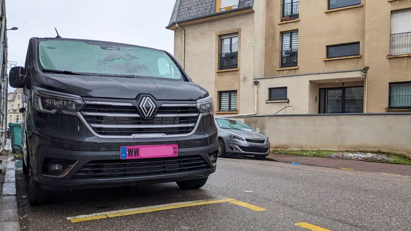 Une voiture garée arborant une plaque d'immatriculation rose.