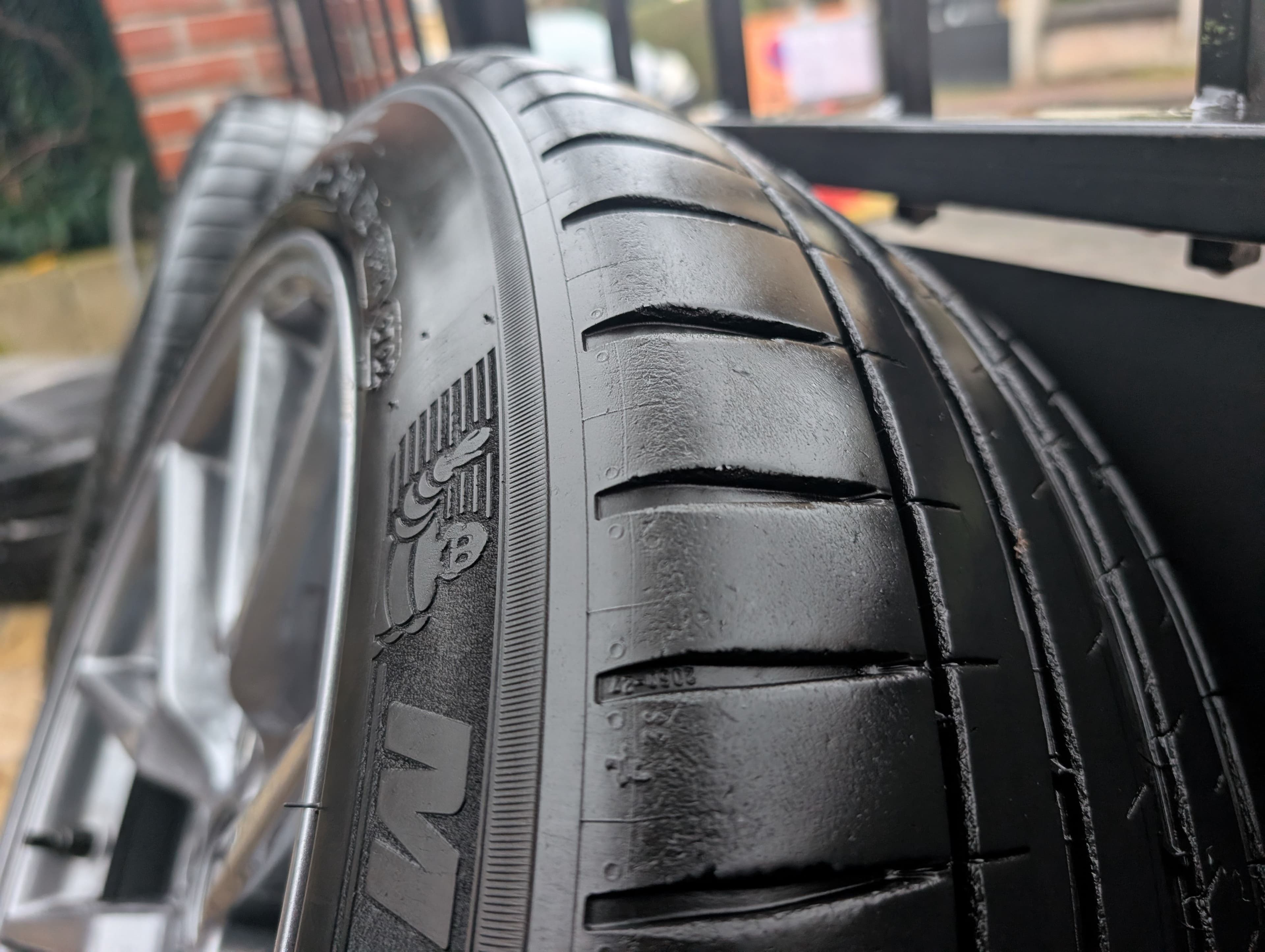 Un pneu posé contre une barrière qui suggère qu'il a été démonté et va être rangé