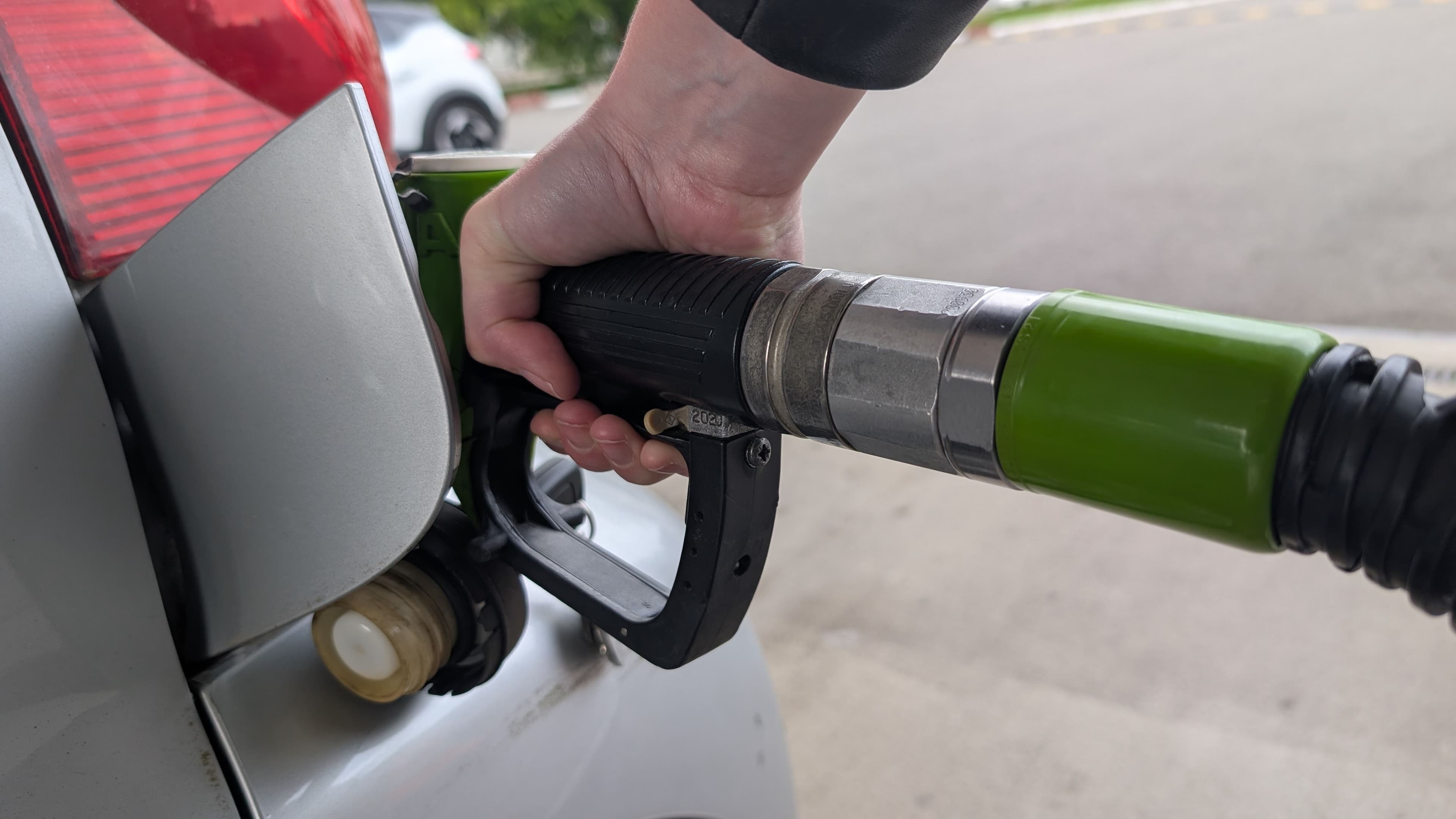 Gros plan sur une main qui tient une pompe à essence et met de l'essence dans son réservoir SP98, SP95-10, SP95, Gasoil, E85, GPL