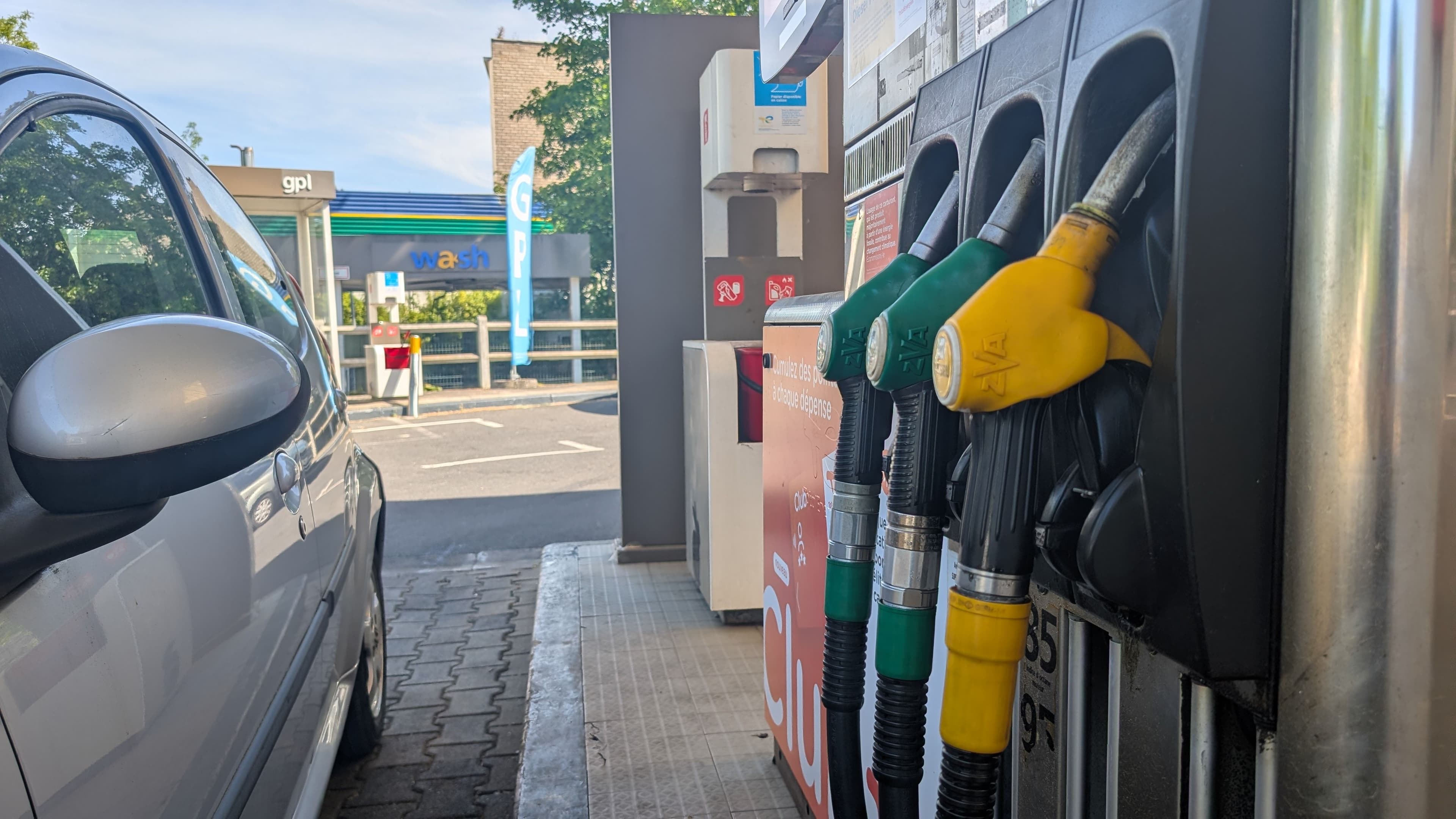 Une voiture prête pour un plein dans une station service, les pistolers des carburants gasoil, SP95 E10 et SP90 sonnt opérationnels