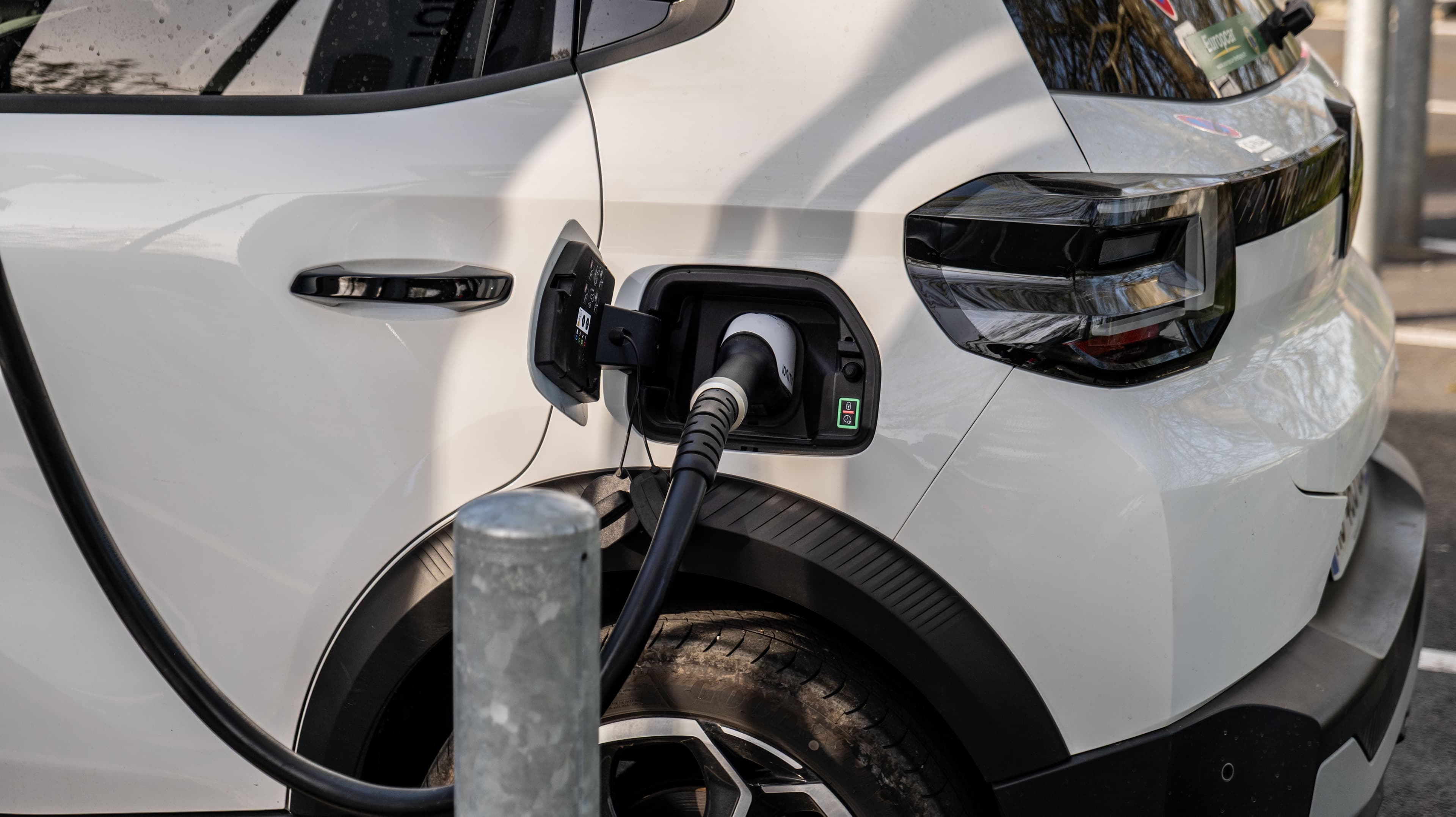 Une voiture électrique blanche branchée, en train de se recharger