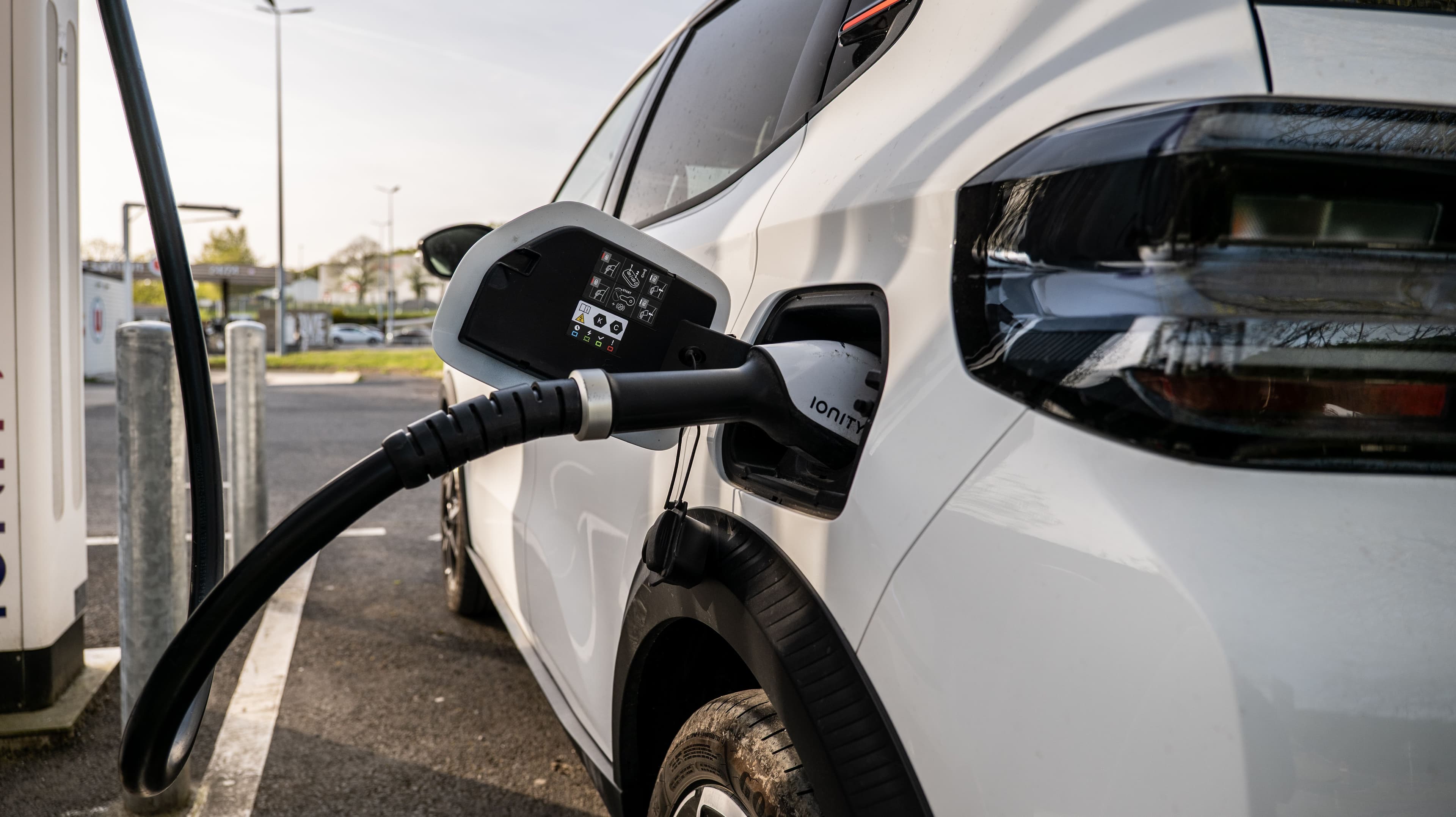 Une voiture électrique blanche branchée sur une borne de recharge rapide