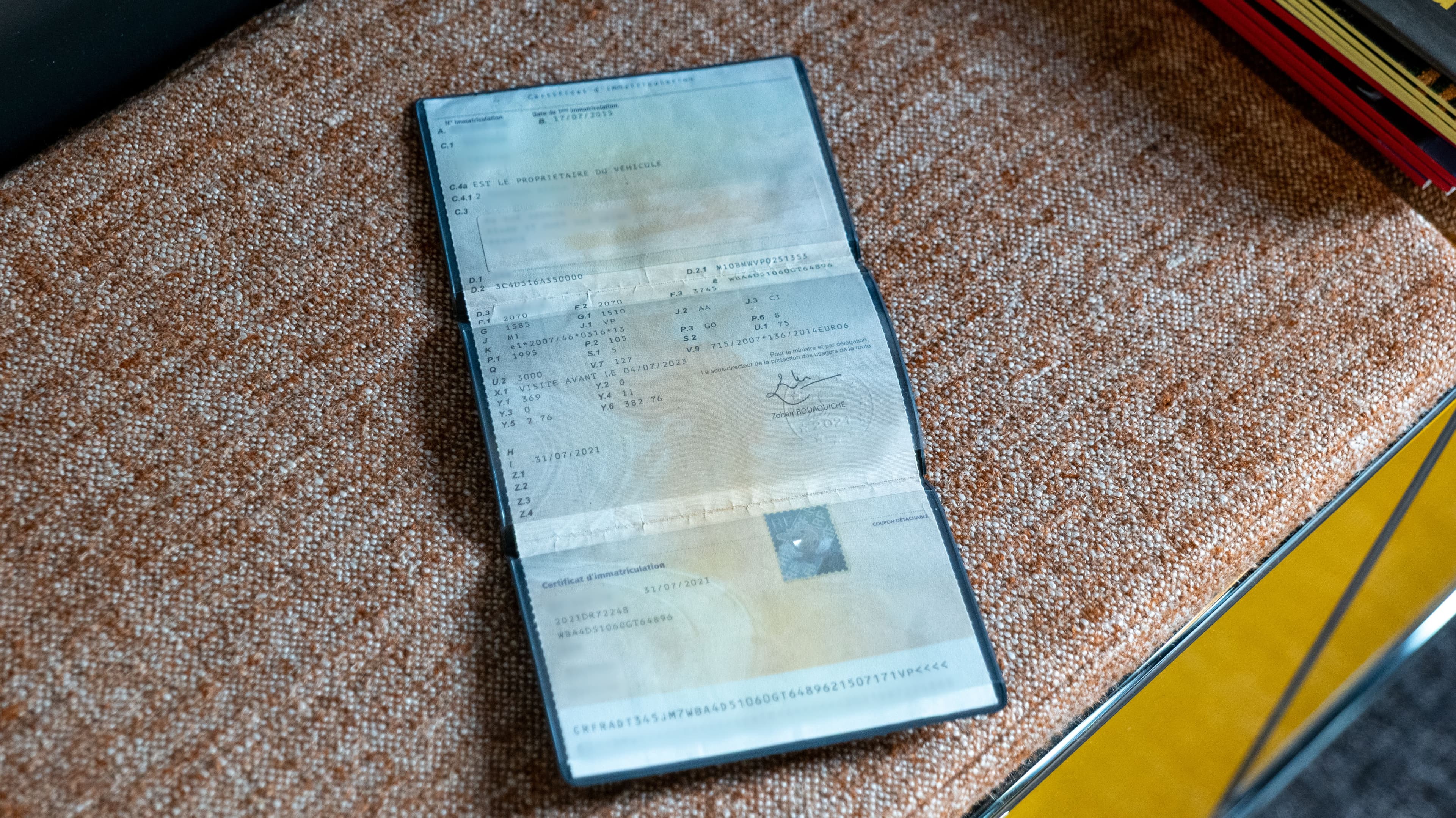 un certification d'immatriculation, ou carte grise, déplié sur une banquette