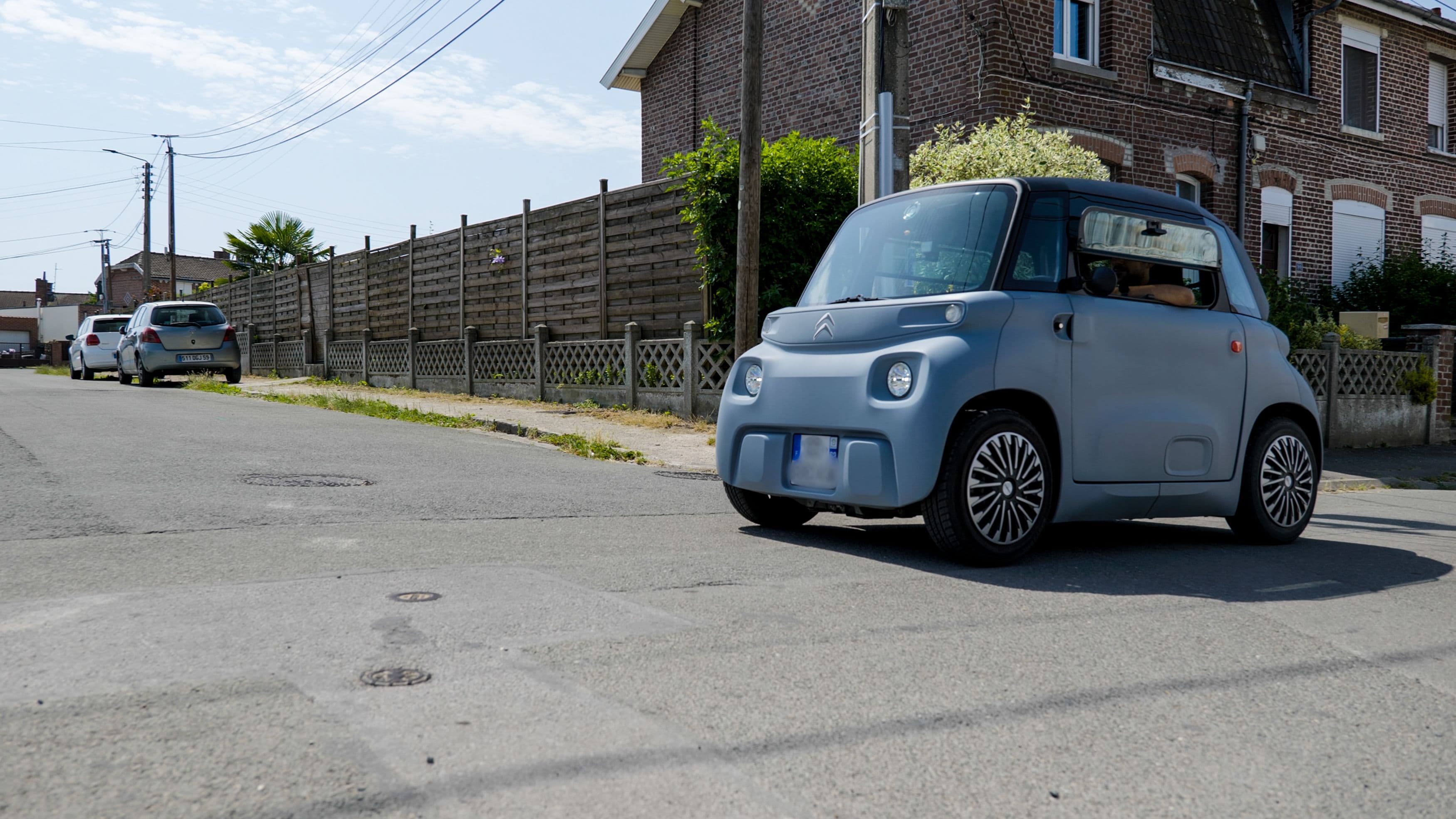 Une Citroën Ami, voiture électrique sans permis, qui roule dans une rue résidentielle en France