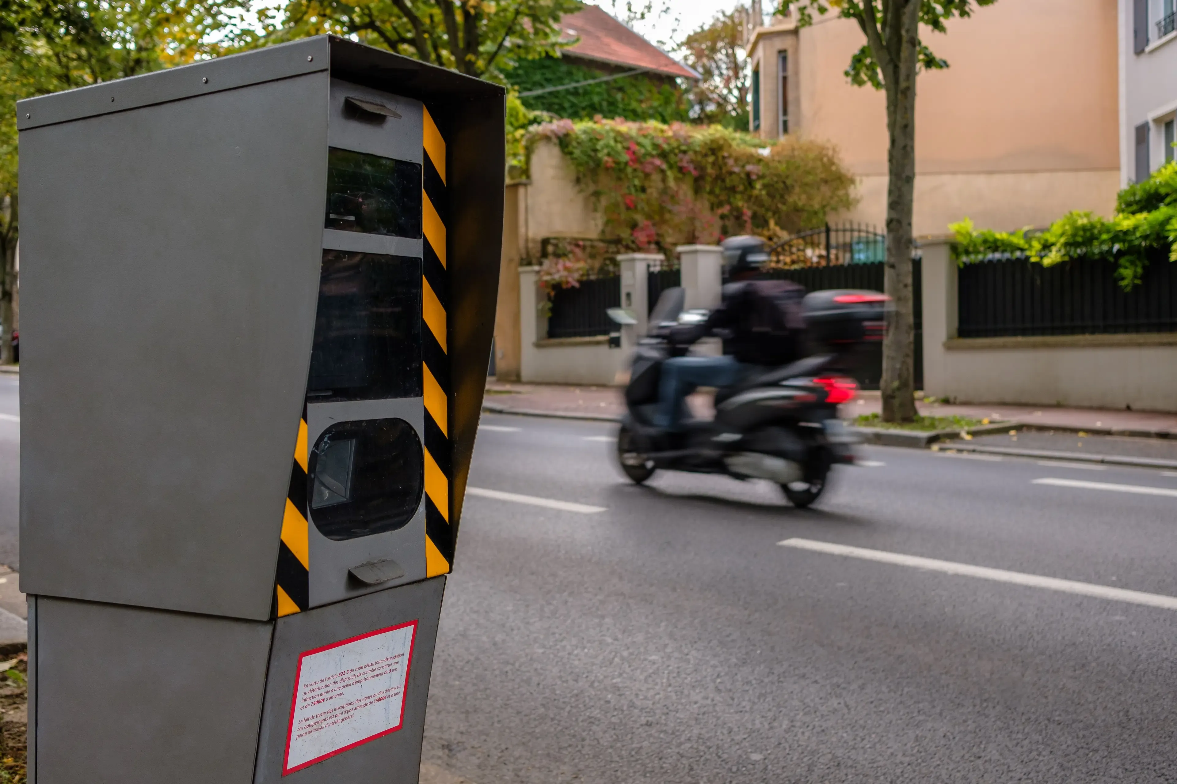 Une moto circulant devant un radar en ville. 