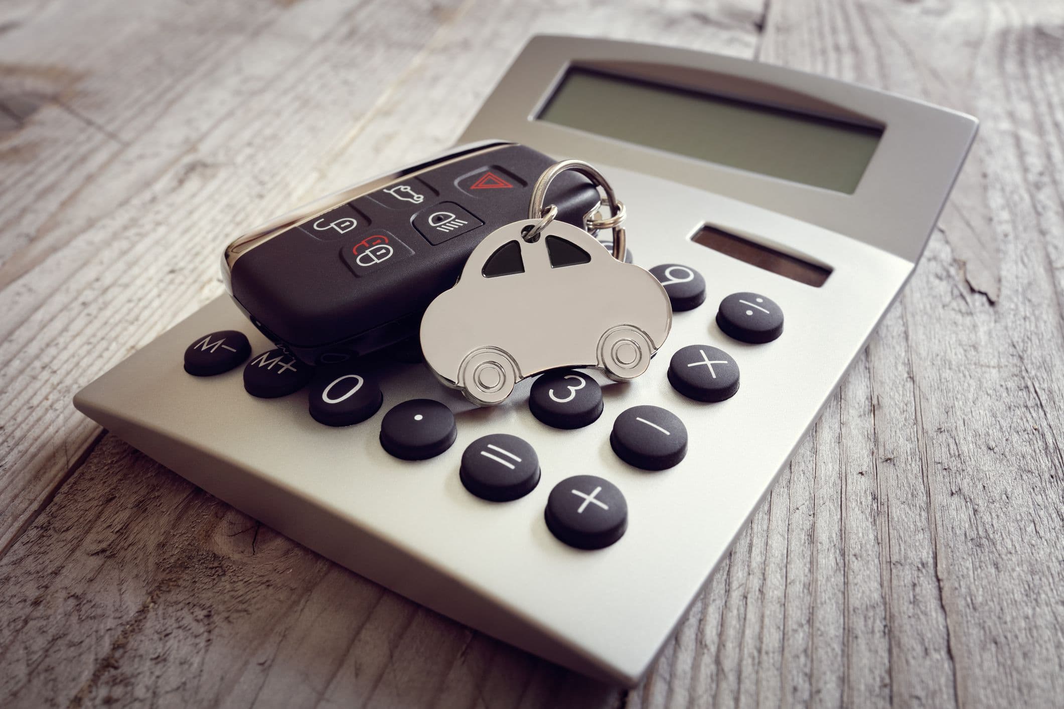 Une calculatrice et une clé de voiture : symboles du budget auto