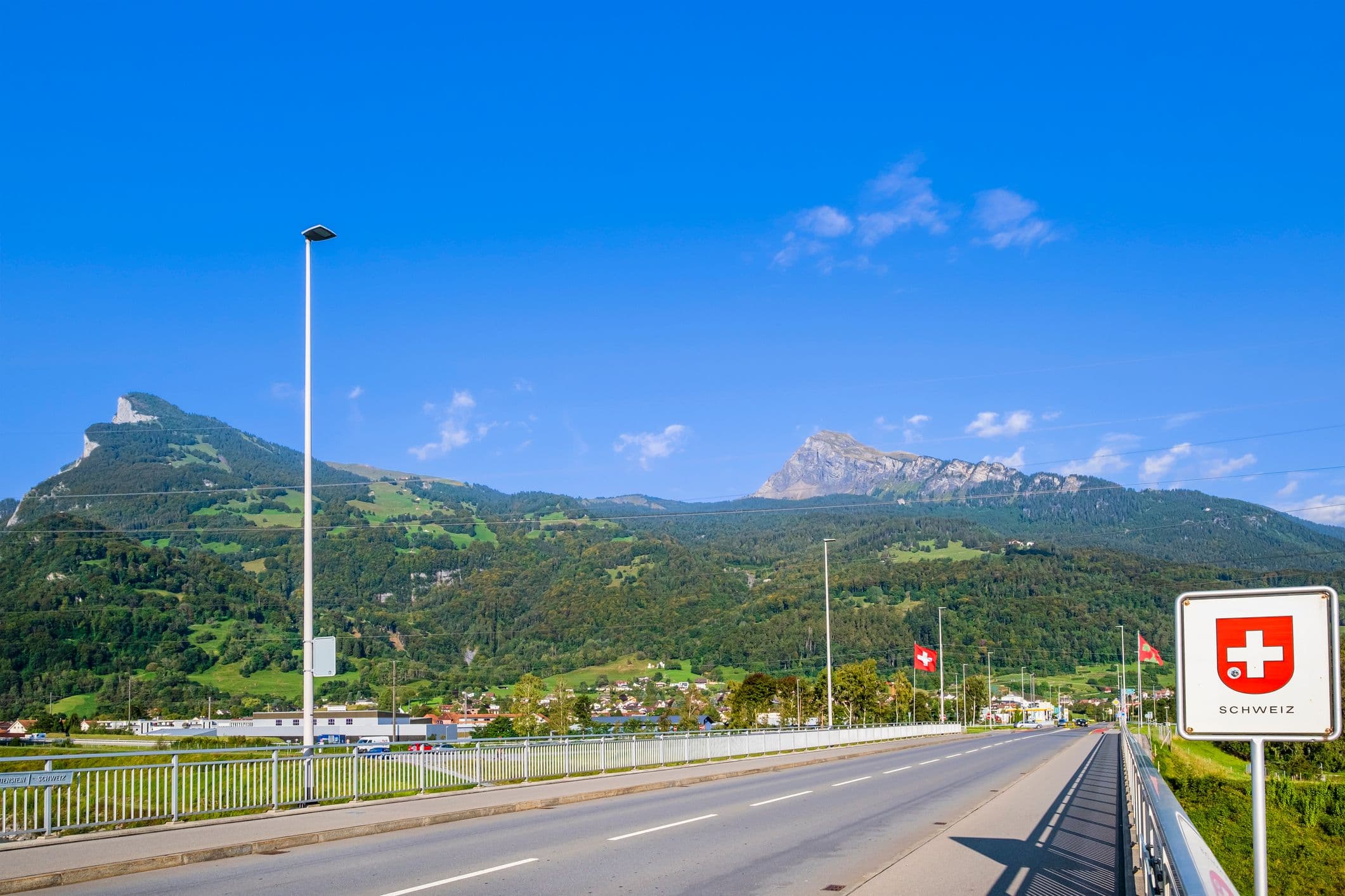 Une route avec un panneau qui indique que l'on rentre en Suisse