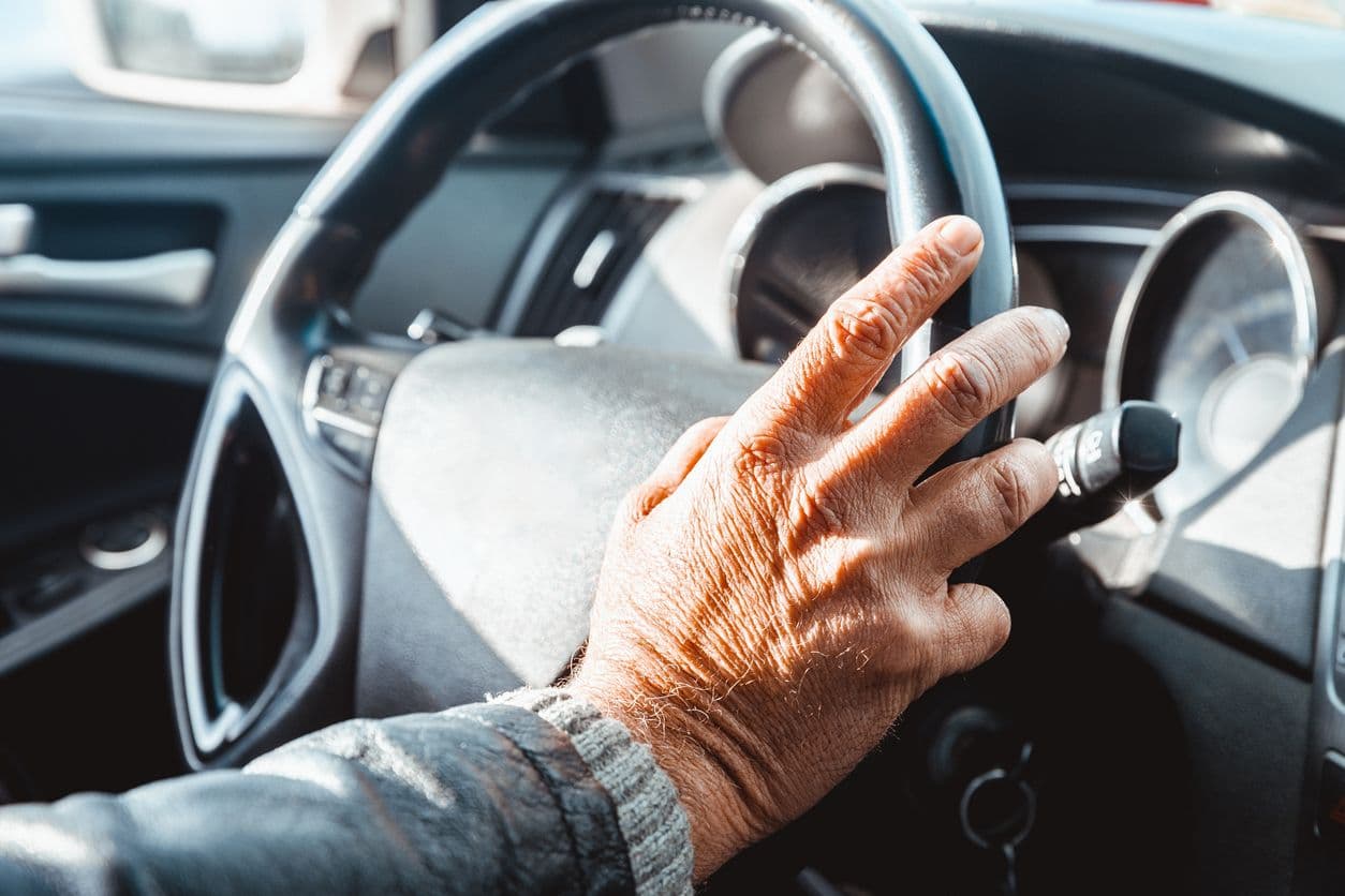 Main d'une personne âgée sur le volant d'une voiture.