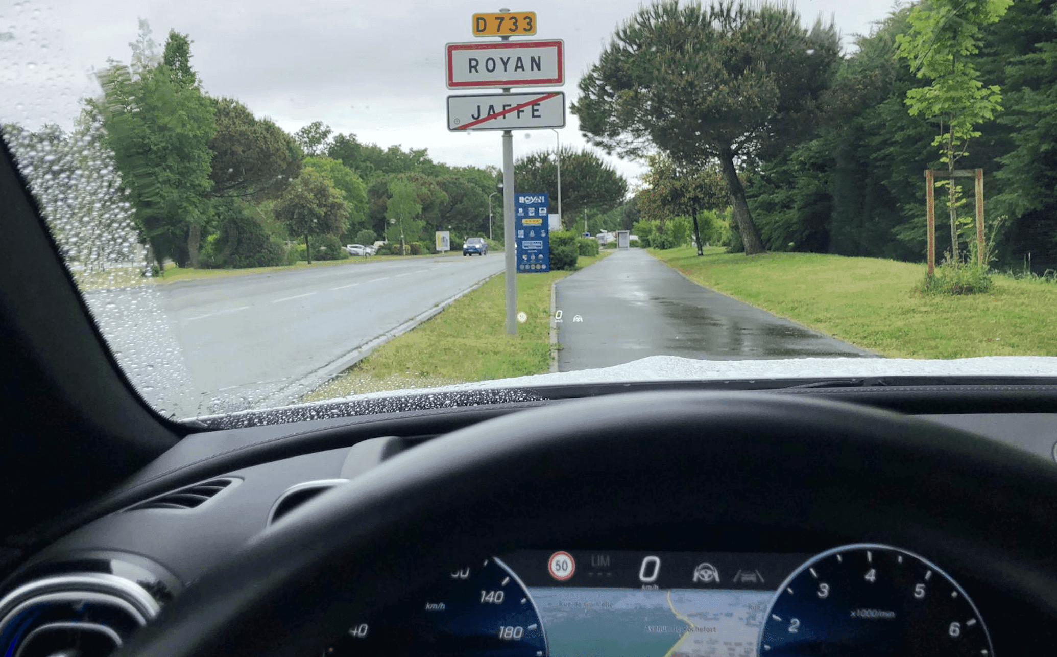Une voiture stationnée près du panneau d'entrée de ville de Royan.
