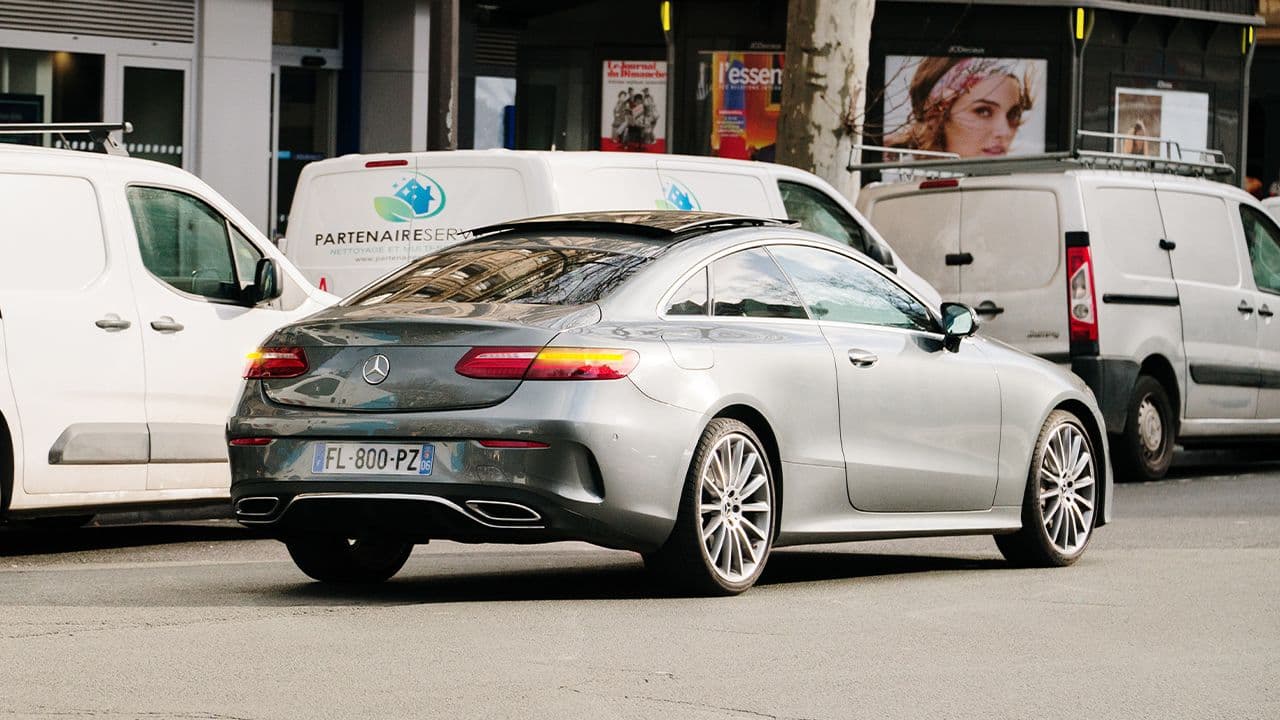 Une voiture en double file avec ses feux de détresse allumés.