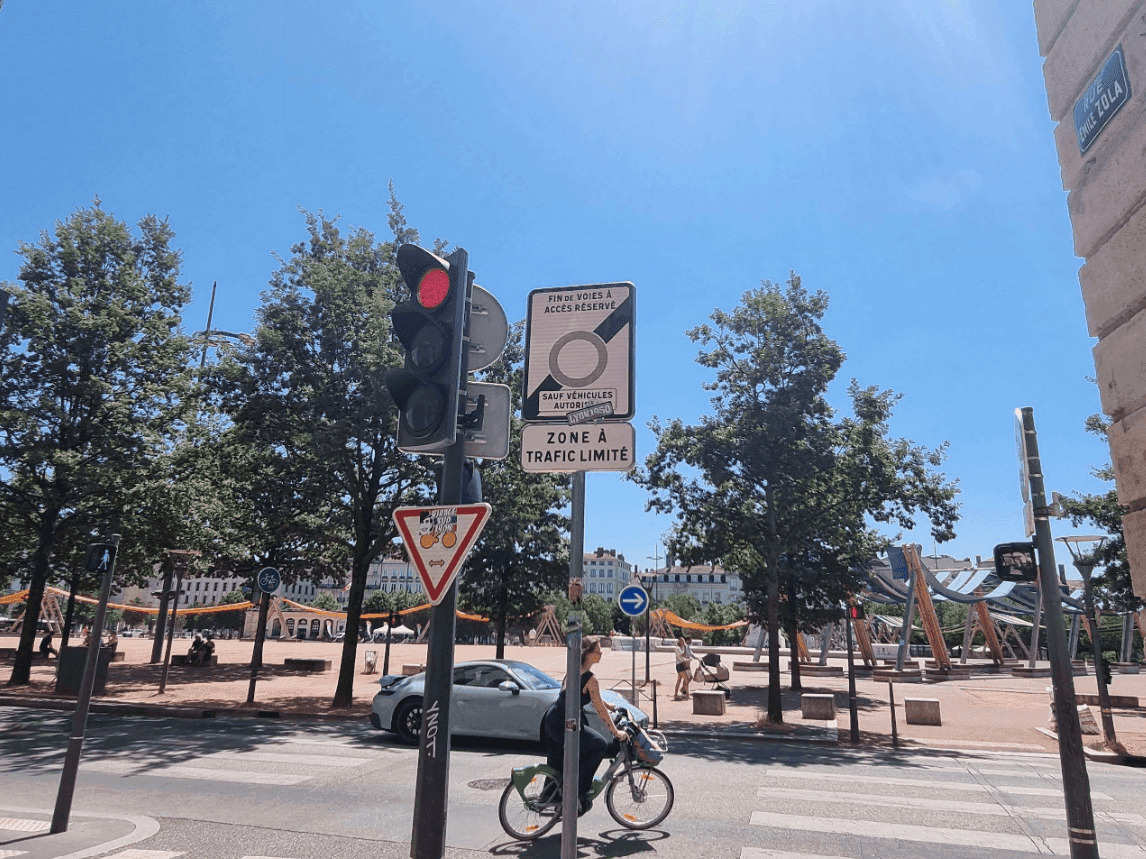 Panneau de zone à trafic limité dans le centre de Lyon, avec une cycliste et une voiture, près de la place Bellecour 