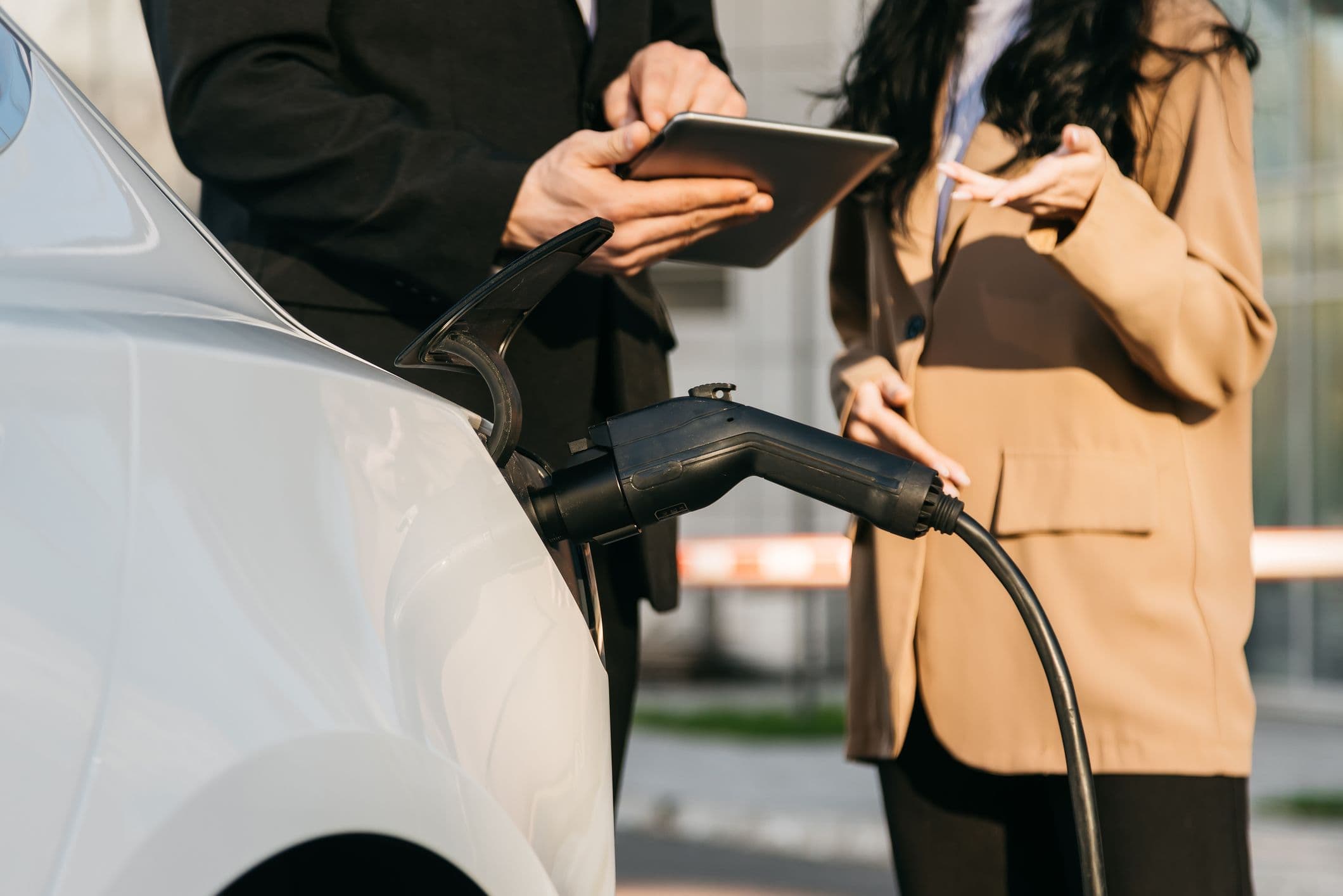 Une acheteuse de voiture électrique en discussion avec un vendeur autour d'une tablette