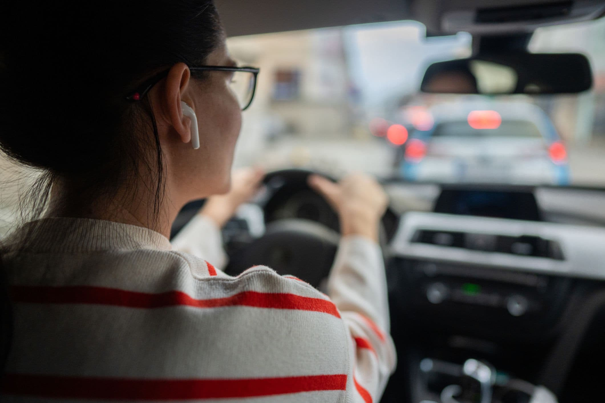 Conductrice portant des écouteurs sans fil et conduisant en ville