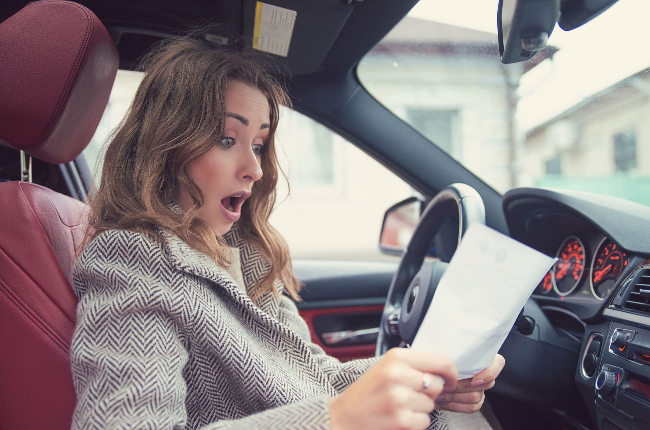 Une femme surprise par une facture dans sa voiture.