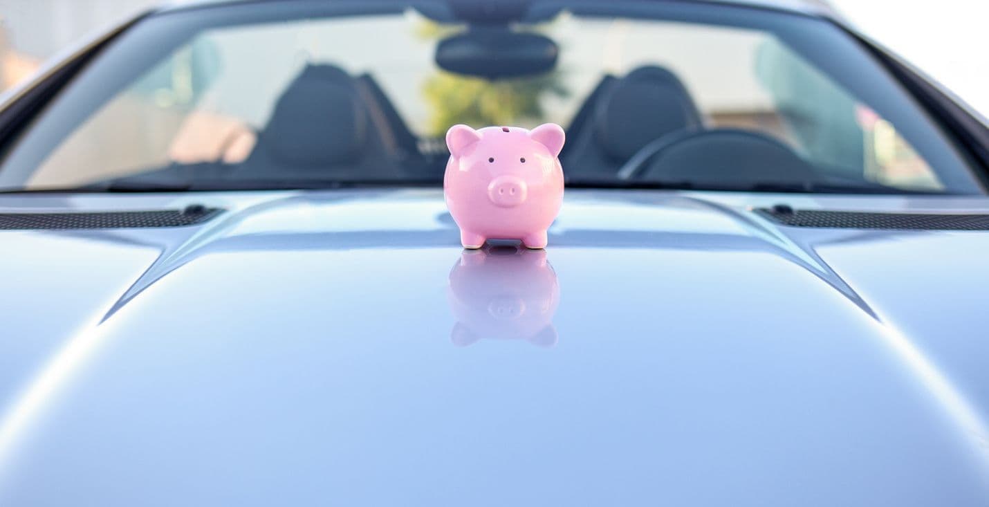 Une tirelire sur le capot d'une voiture. 