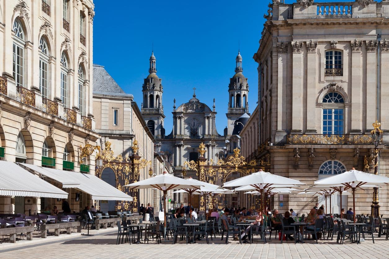 Vue sur la cathédrale de Nancy depuis une place, avec une terrasse de café