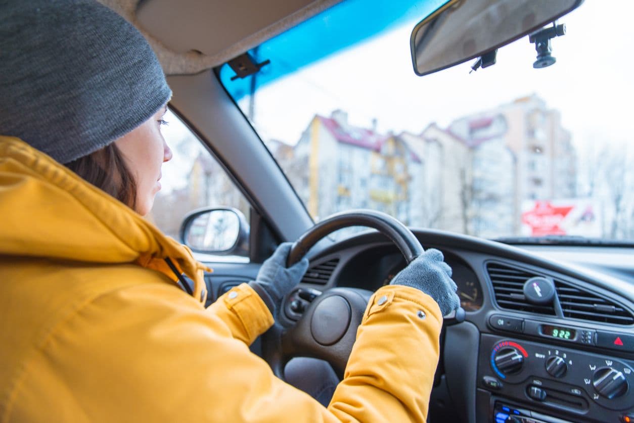 une femme conduit avec une grosse veste et des gants