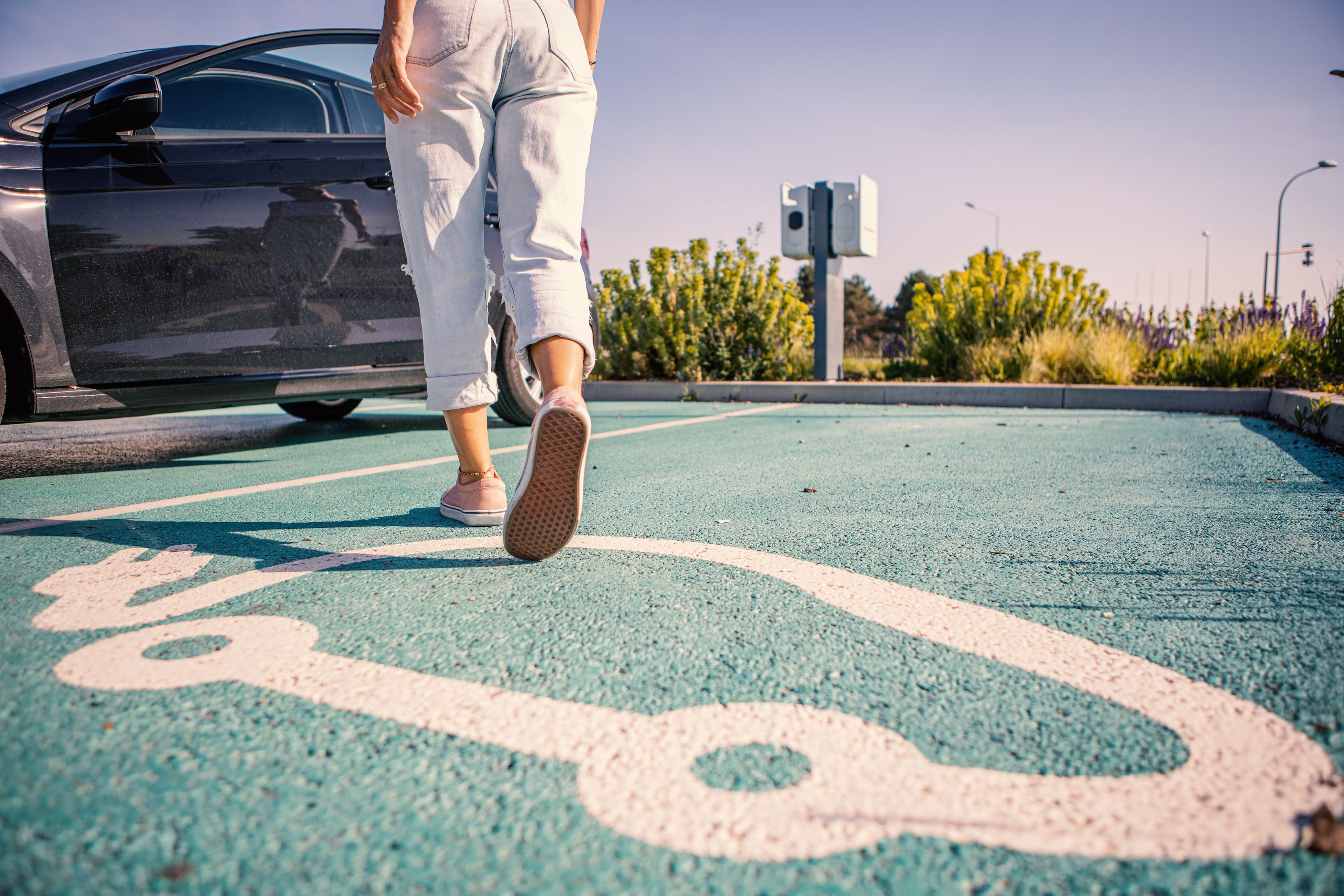 Une personne rejoint sa voiture électrique sur un parking