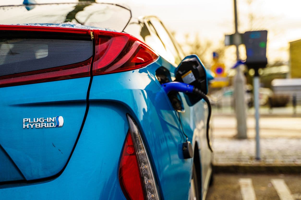 Une voiture hybride rechargeable en train de recharger sur une borne publique