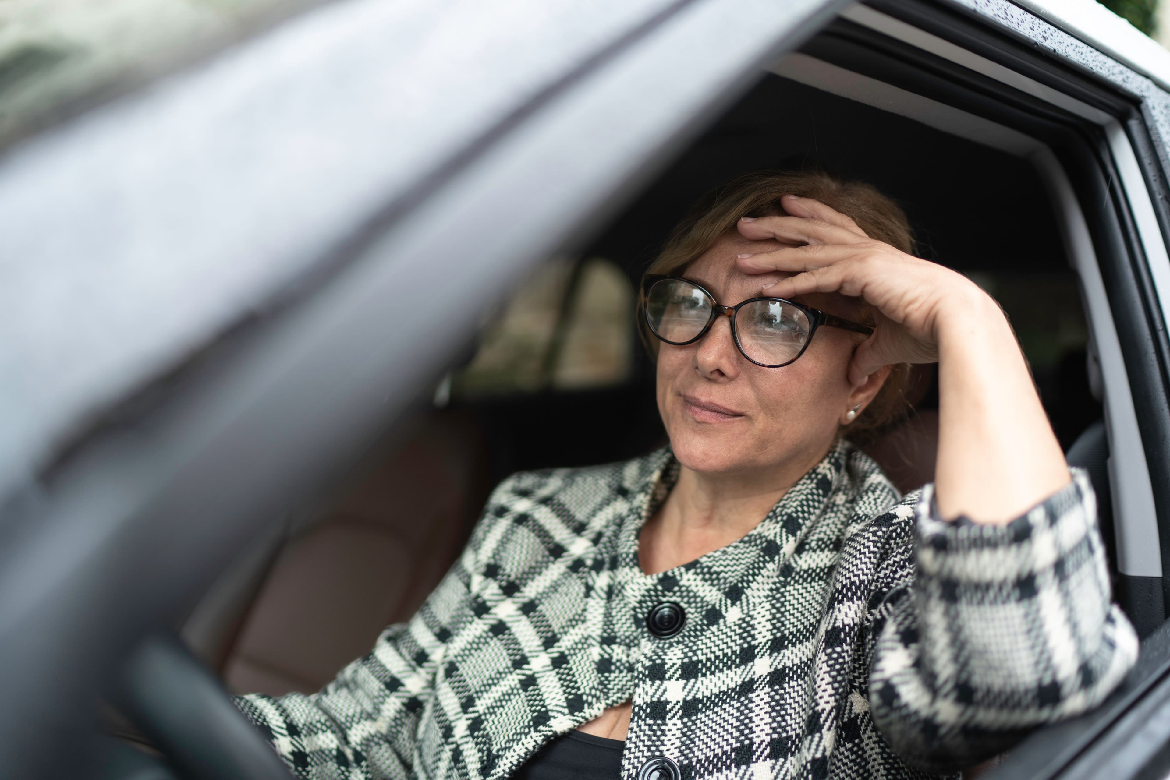 Une femme seule au volant de sa voiture, met sa main sur son front