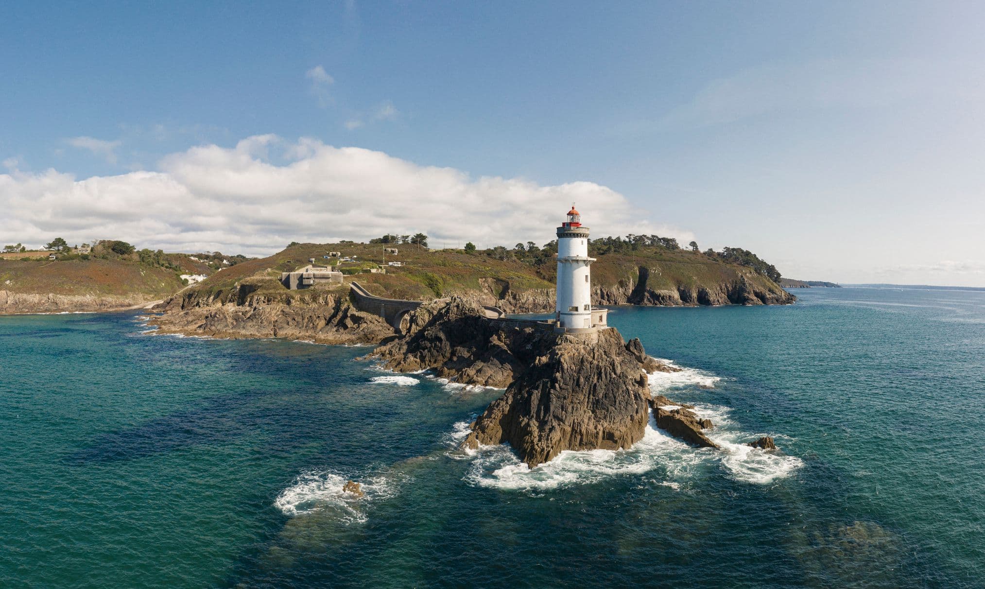 Côte bretonne avec un phare emblématique, des falaises escarpées et la mer agitée, illustrant la richesse du patrimoine naturel et culturel de la Bretagne, parfaite illustration pour un quiz interactif sur la région