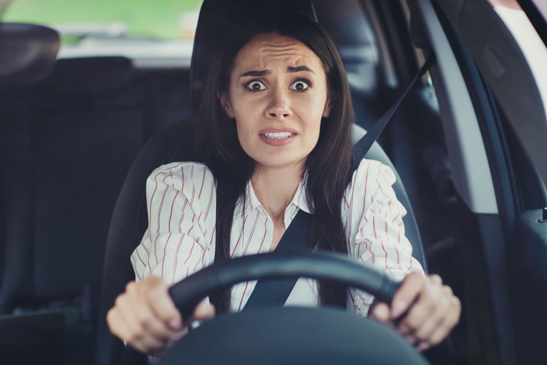 Femme effrayée au volant de sa voiture en panne sur l’autoroute, illustrant le stress et les dangers d’une panne sur l'autoroute.