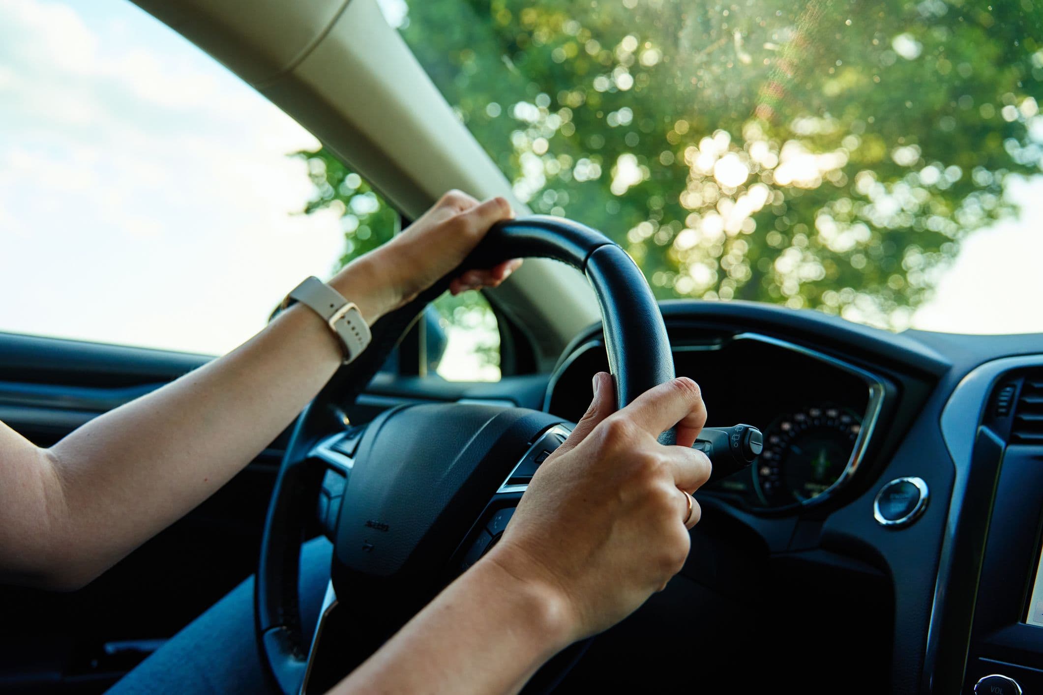 Mains de femme sur le volant, elle pratique l'éco-conduite