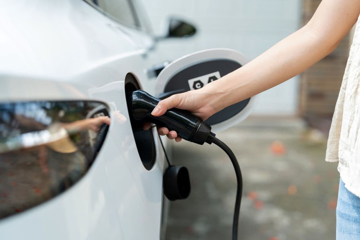 Une femme tient le câble de recharge de sa voiture électrique