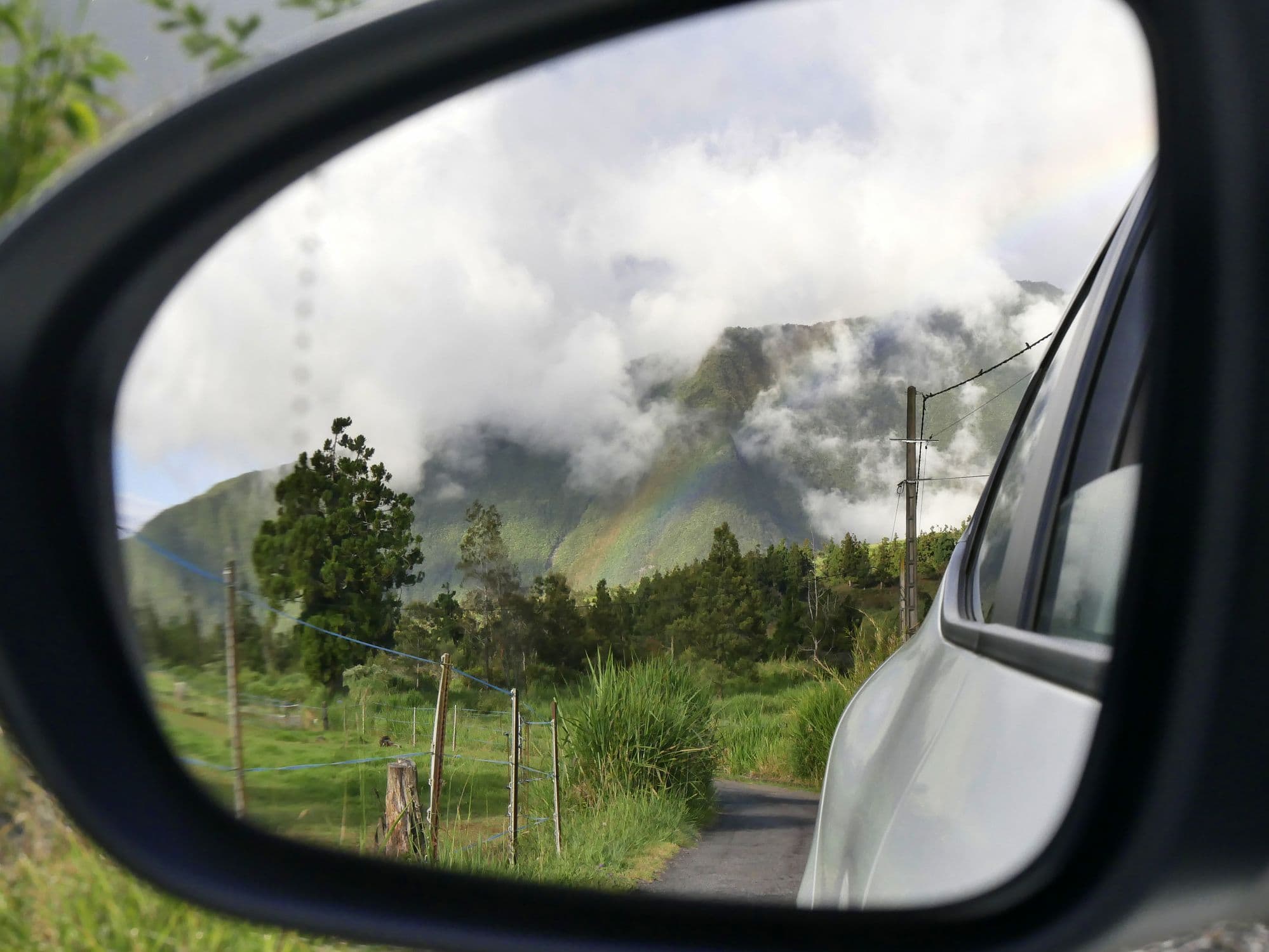 Une route de La Réunion vue dans le rétroviseur d'une voiture. 