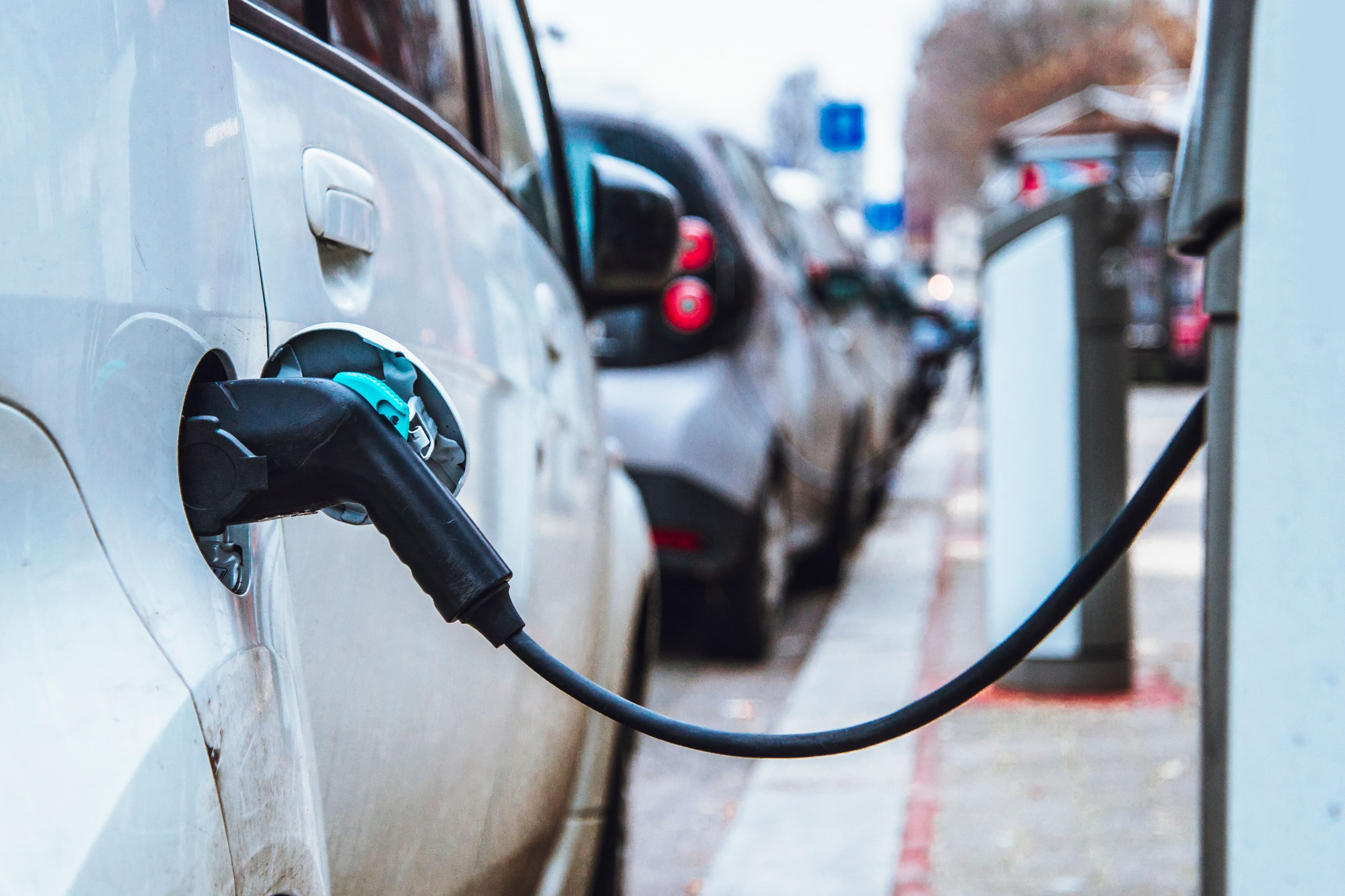 une voiture électrique en train de se recharger sur une borne publique dans la rue