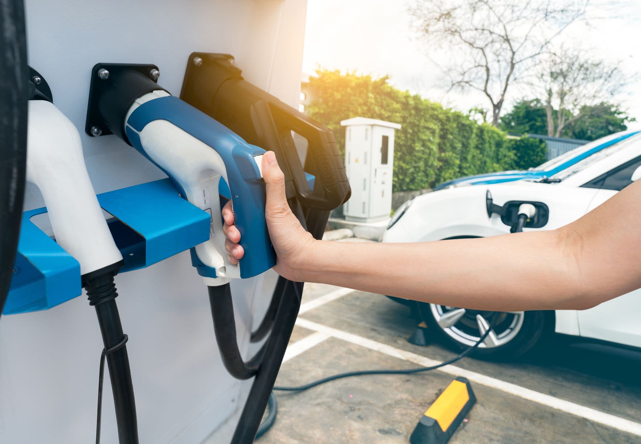 Une personne s'apprête à recharger sa voiture électrique dans une station de recharge rapide