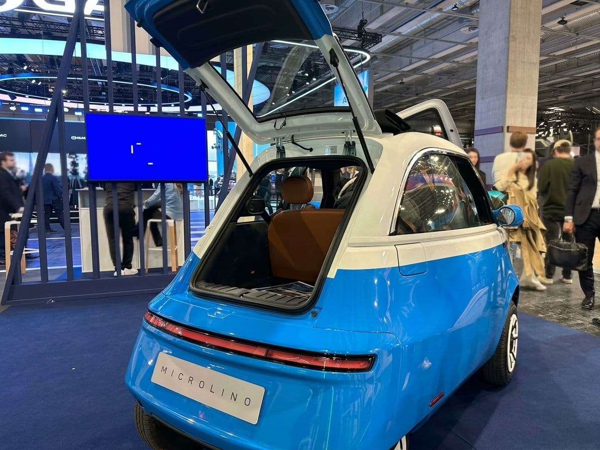 Microcar Microlino bleu et blanc avec coffre ouvert en exposition sur le Mondial de l'Auto de Paris 2026